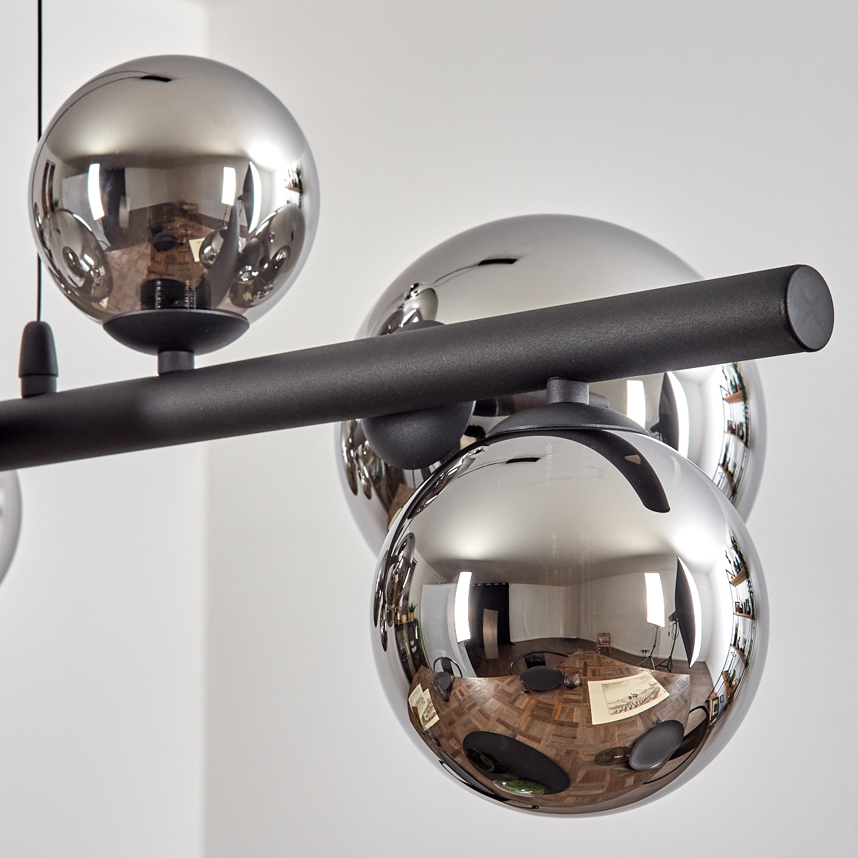 Eine moderne Lampe mit mehreren spiegelnden Kugeln an einem schwarzen Stab.