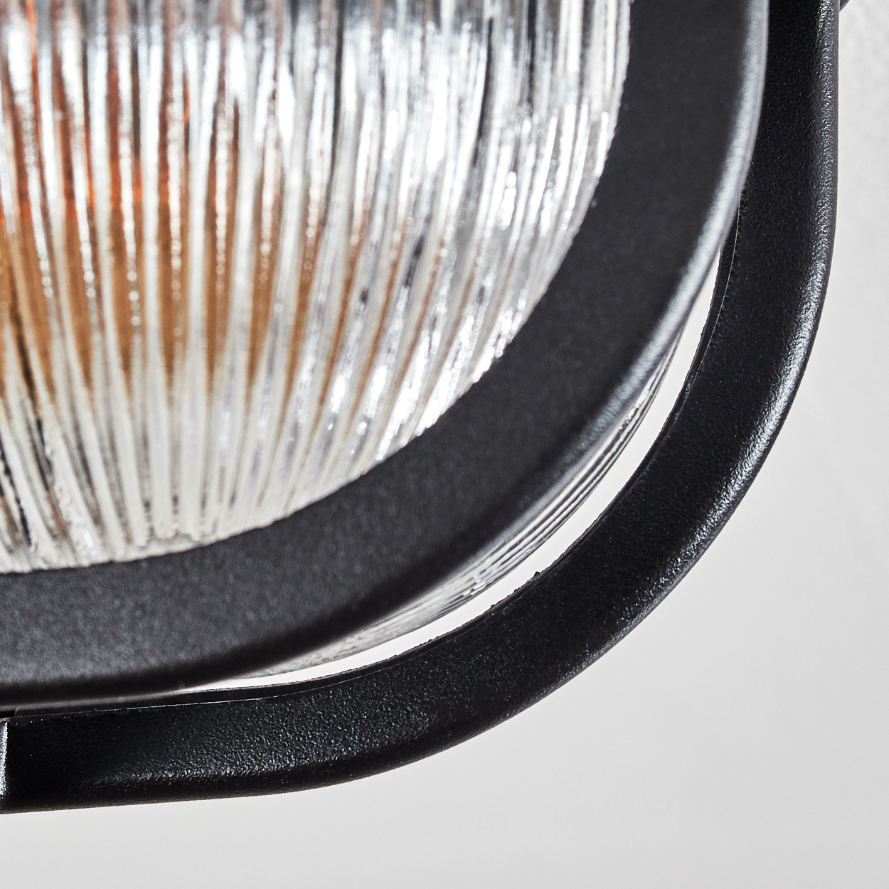 Nahaufnahme einer Lampe mit geriffeltem Glas und schwarzem Metallrahmen.