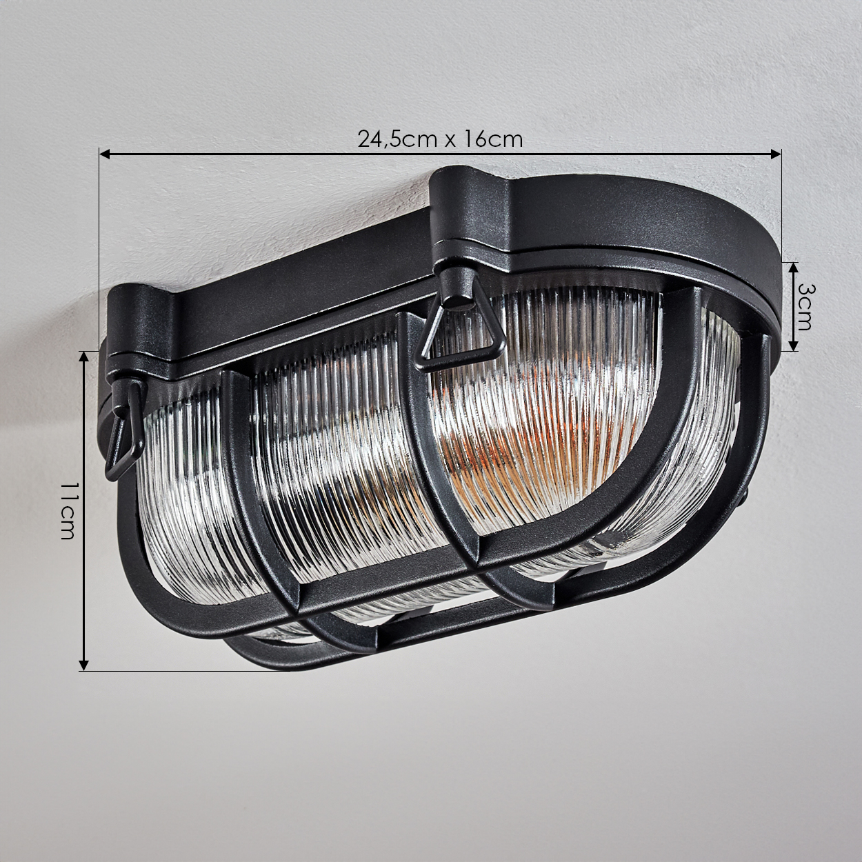 Schwarze Wandleuchte mit geripptem Glas und Metallschutzgitter.