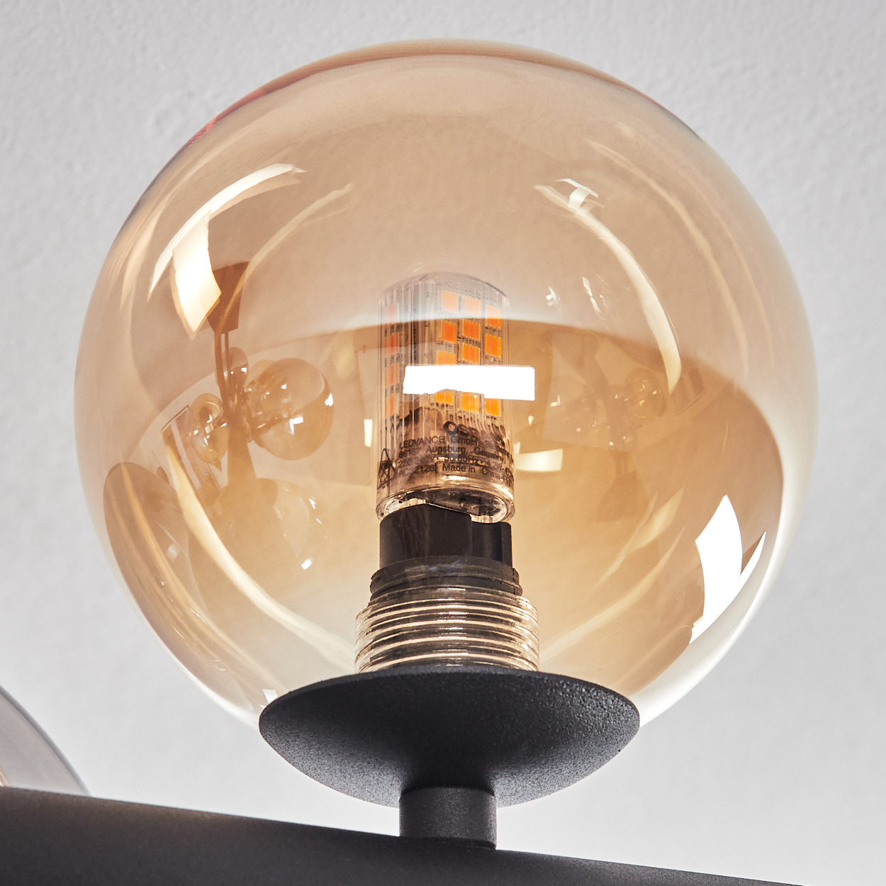Eine bernsteinfarbene Glaskugel umgibt eine LED-Lampe mit orangefarbenen Lichtern.