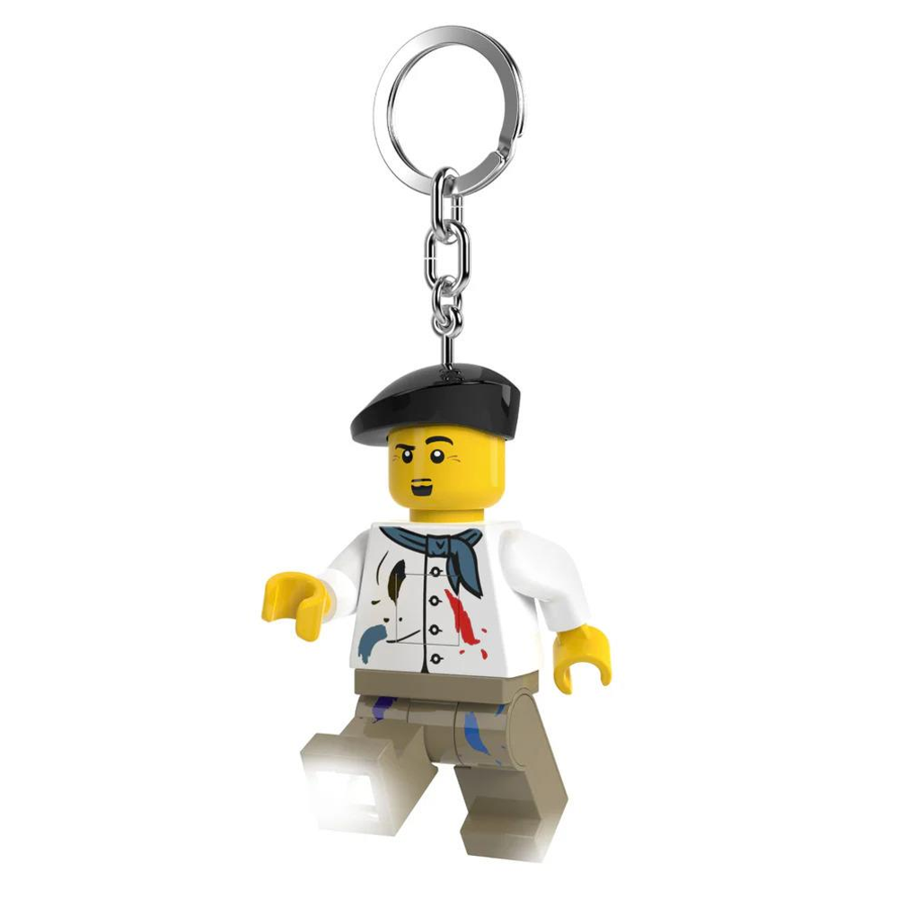 Bereli ve eşarplı bir ressamı gösteren Lego anahtarlık. Pantolonunda boya lekeleri var.