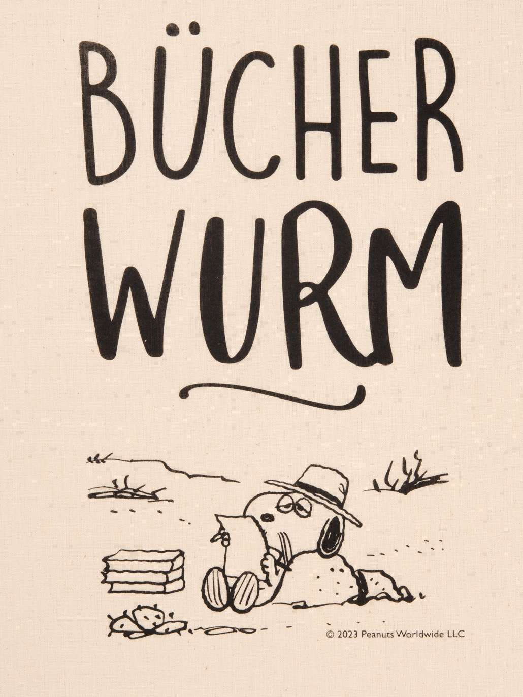 Snoopy liest mit Hut und Brille, daneben Bücher. Text: Bücherwurm.