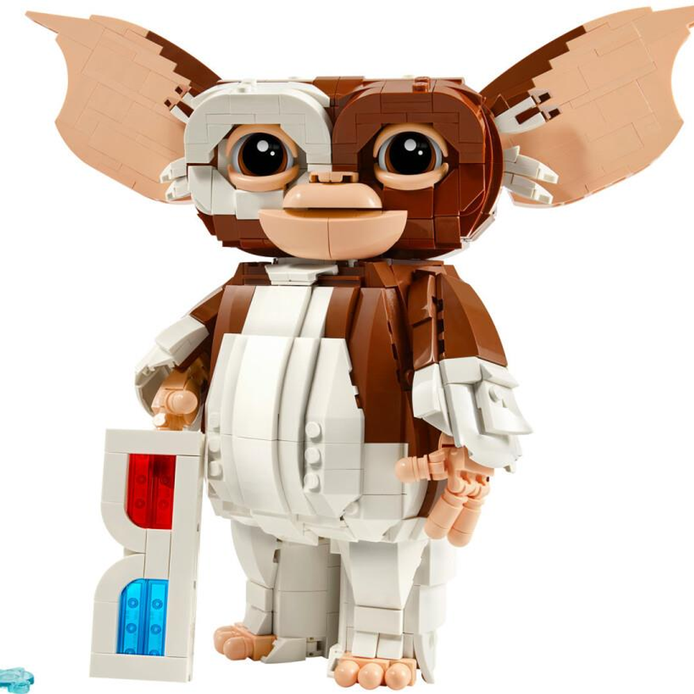 Brązowo-biała figurka Lego Gizmo trzyma niebiesko-czerwony przedmiot.
