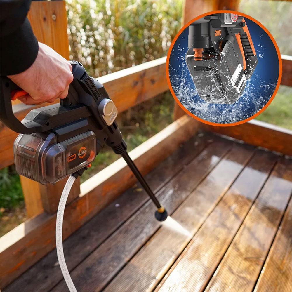 Persona pulisce terrazza in legno con idropulitrice a batteria. Spruzza acqua.