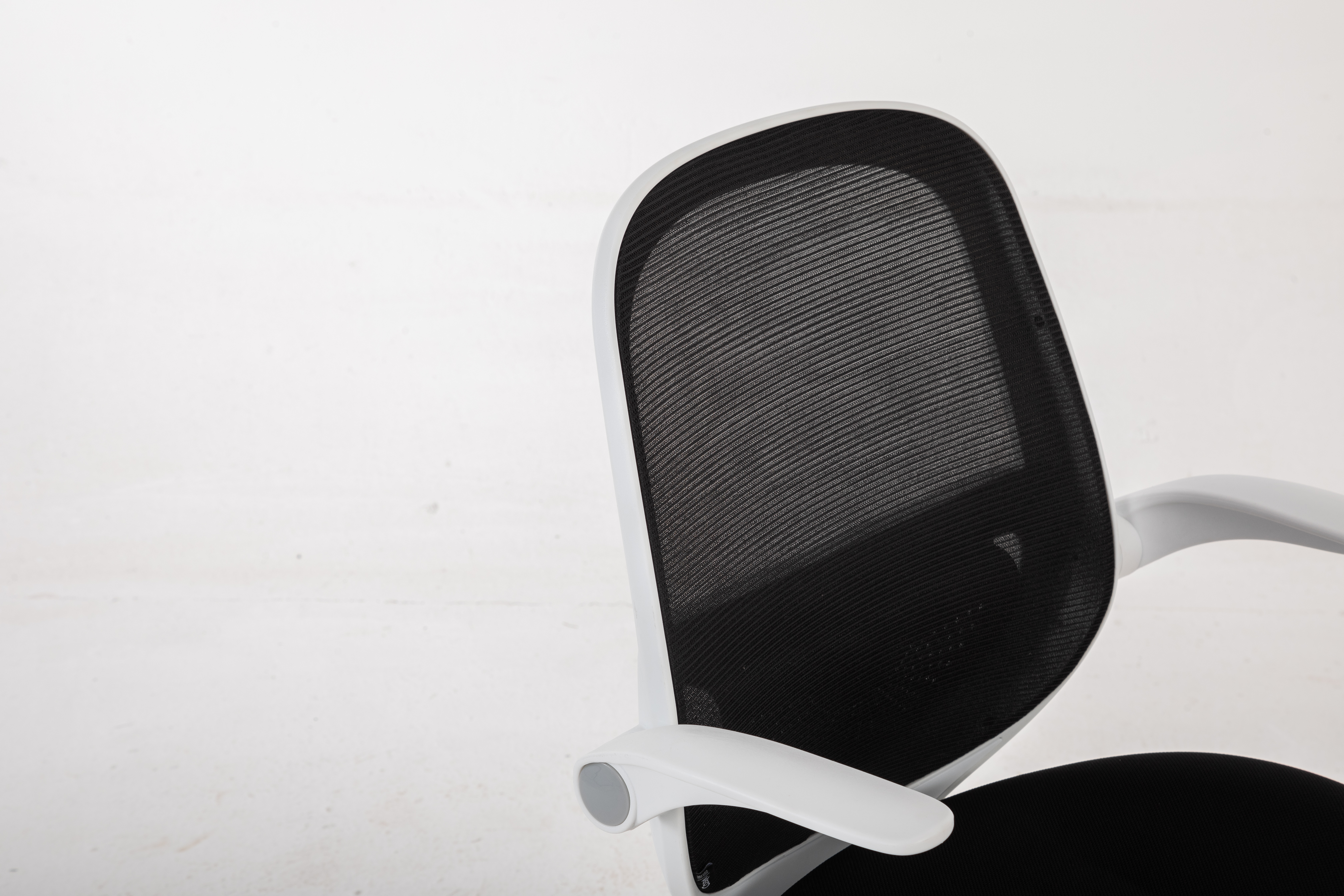 Nowoczesne krzesło biurowe z czarnym oparciem z siatki i białymi podłokietnikami.