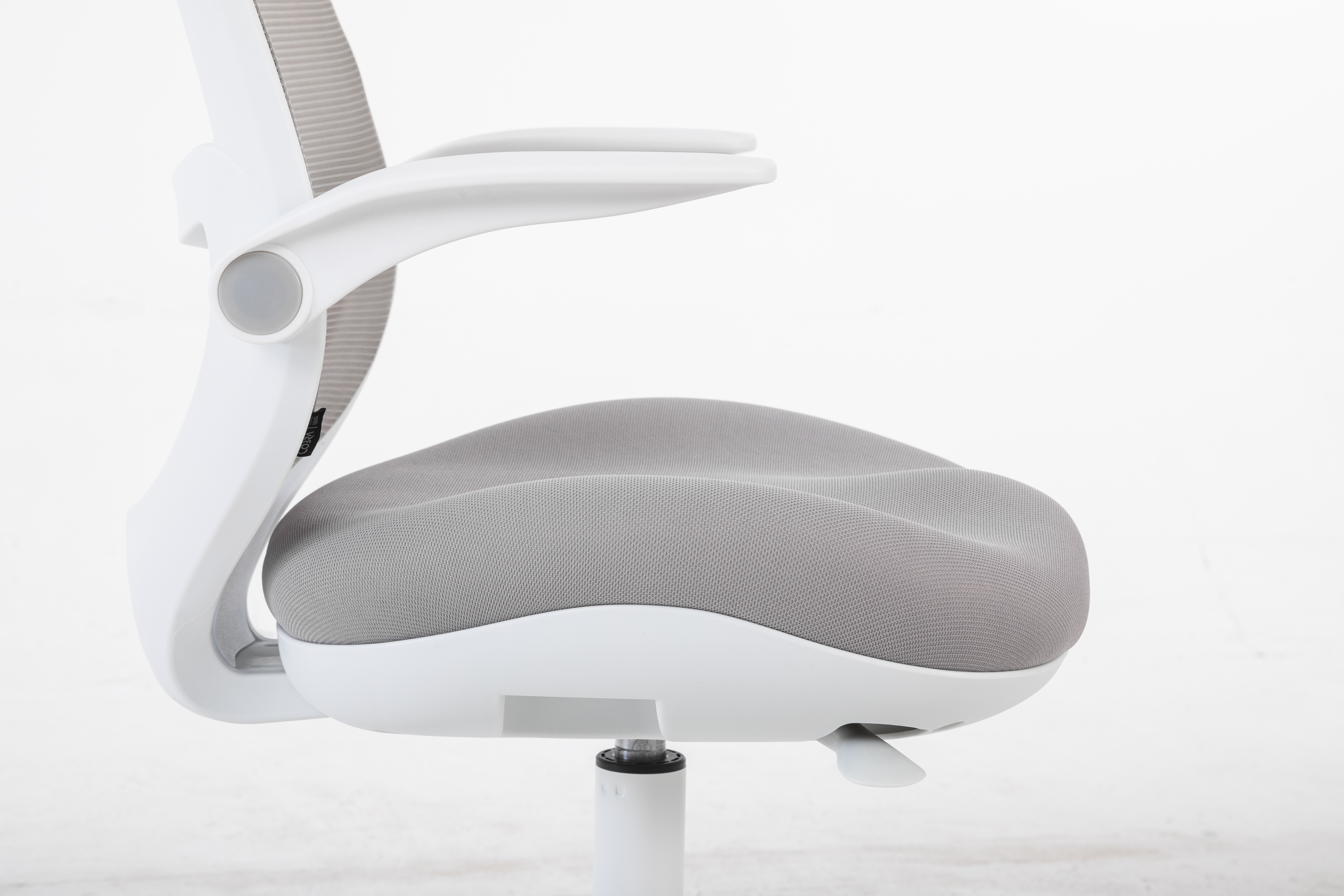 Białe krzesło biurowe z szarej siateczki. Zbliżenie na siedzisko i podłokietnik.