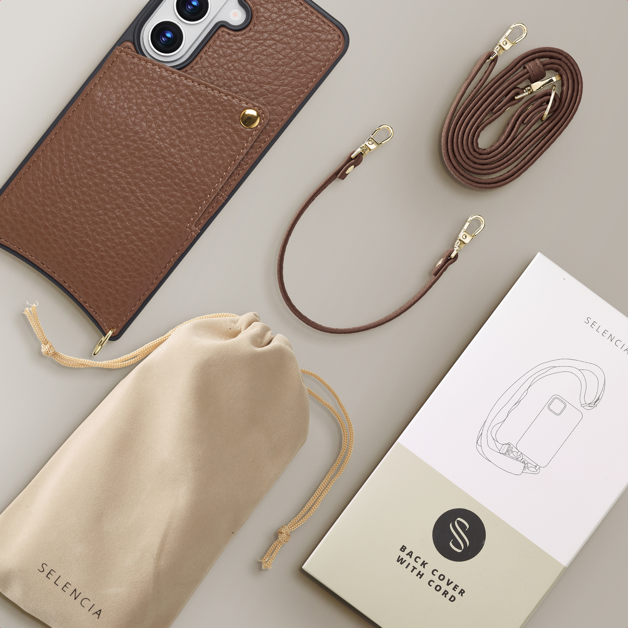 Coque de téléphone en cuir marron avec cordon, pochette et boîte sur fond gris.