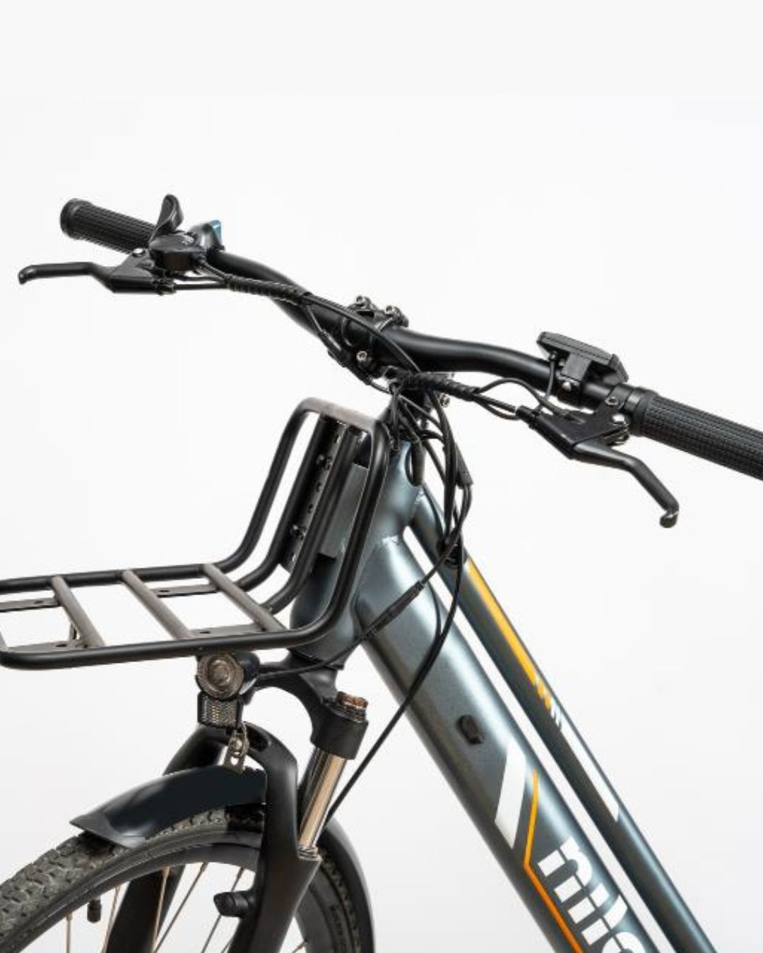 Primo piano di una e-bike grigia che mostra manubrio, portapacchi anteriore e ruota anteriore.