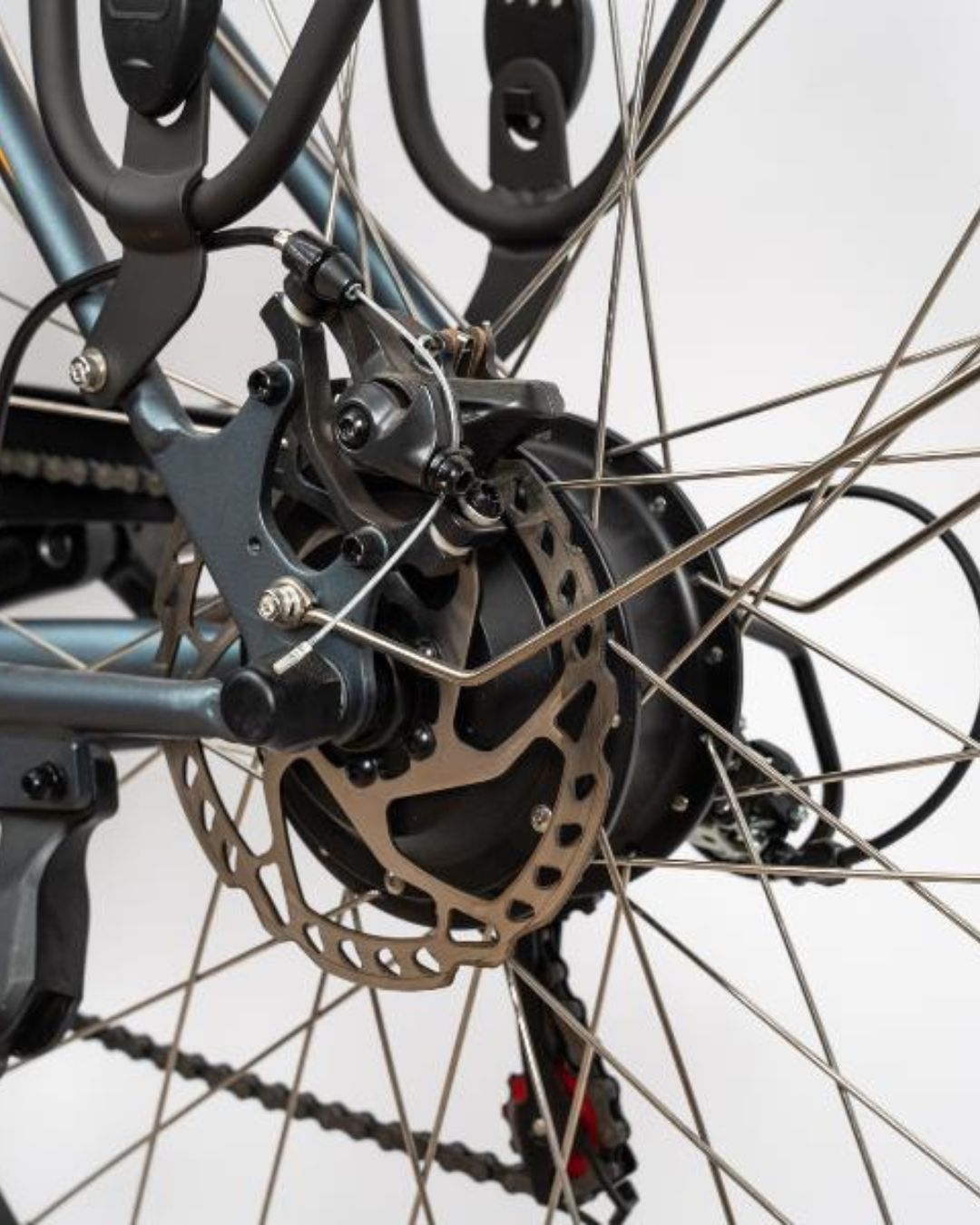 Primo piano del mozzo di una bicicletta con raggi, disco freno e catena.