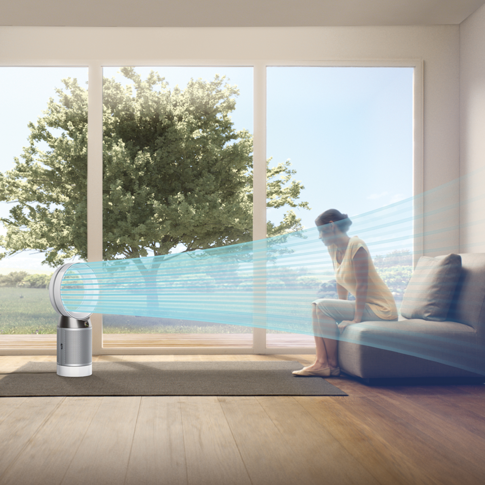 Un purificador de aire Dyson sopla aire hacia una mujer sentada en un sofá.