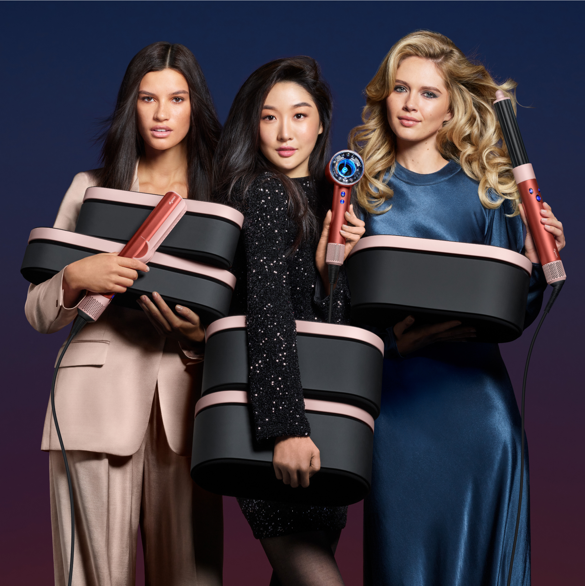 Drei Frauen mit Haarstyling-Geräten und Aufbewahrungsboxen. Dunkler Hintergrund.