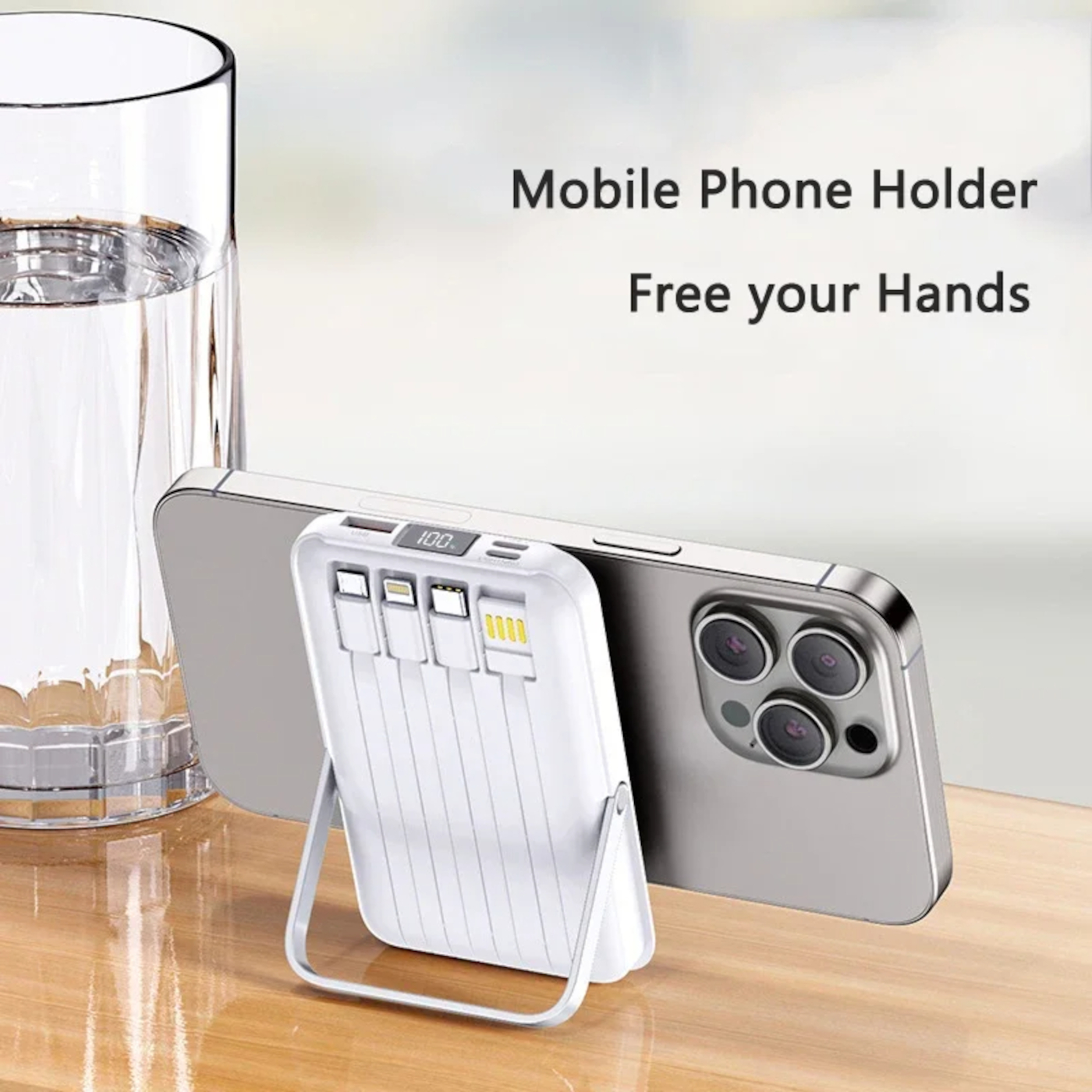 Ein weißer Handyhalter mit integrierten Kabeln stützt ein silbernes Smartphone neben einem Glas Wasser.