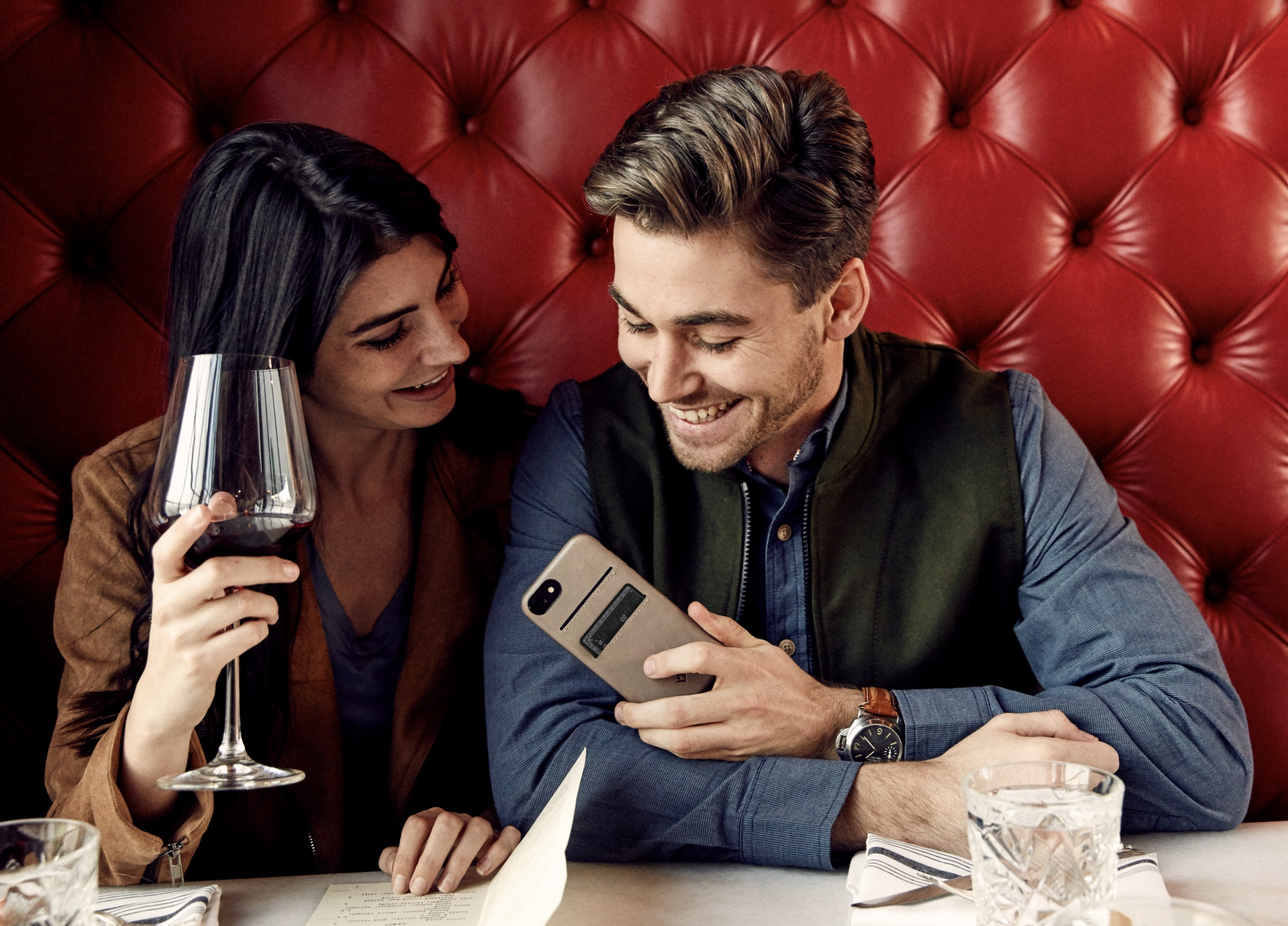 Un homme et une femme sont assis à une table devant un fond rouge capitonné.