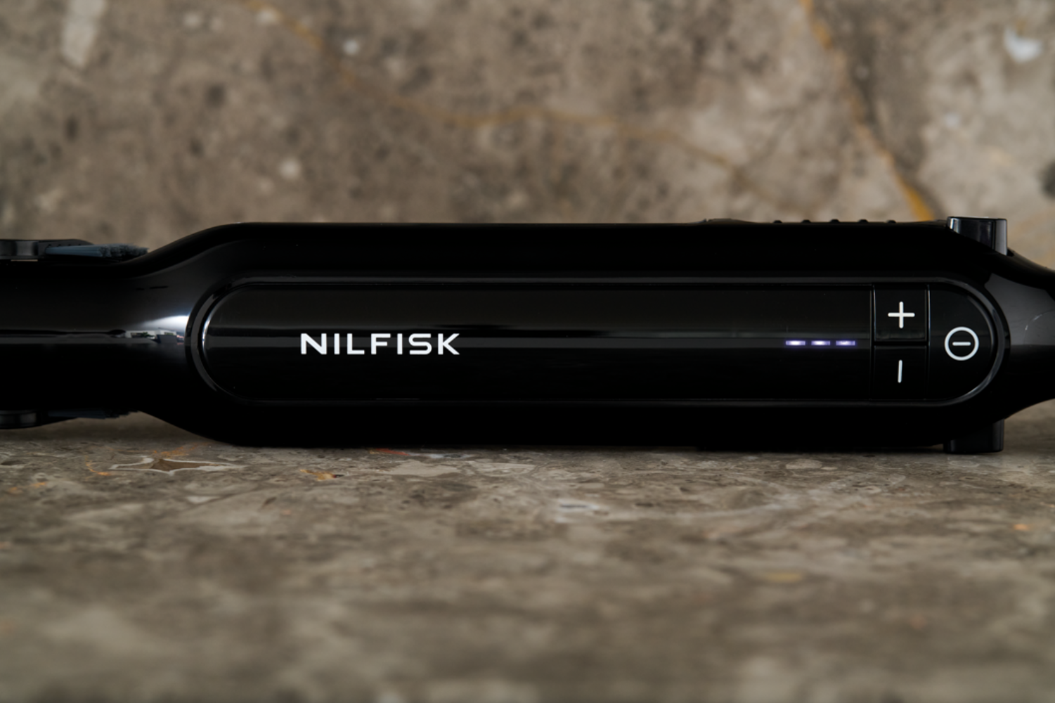Dispositivo negro con logo NILSFIK y controles sobre fondo de mármol.