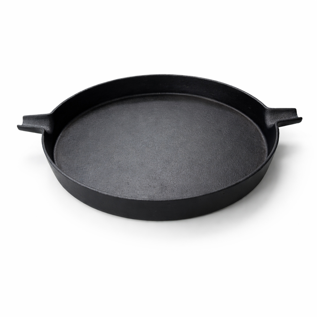 A black cast iron skillet with two handles, set against a white background.