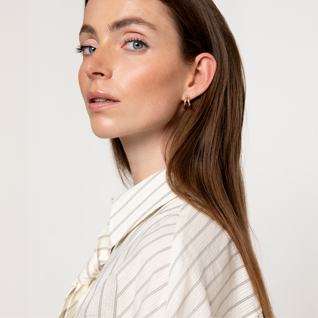Close up of a woman with blue eyes and brown hair, wearing a striped shirt.