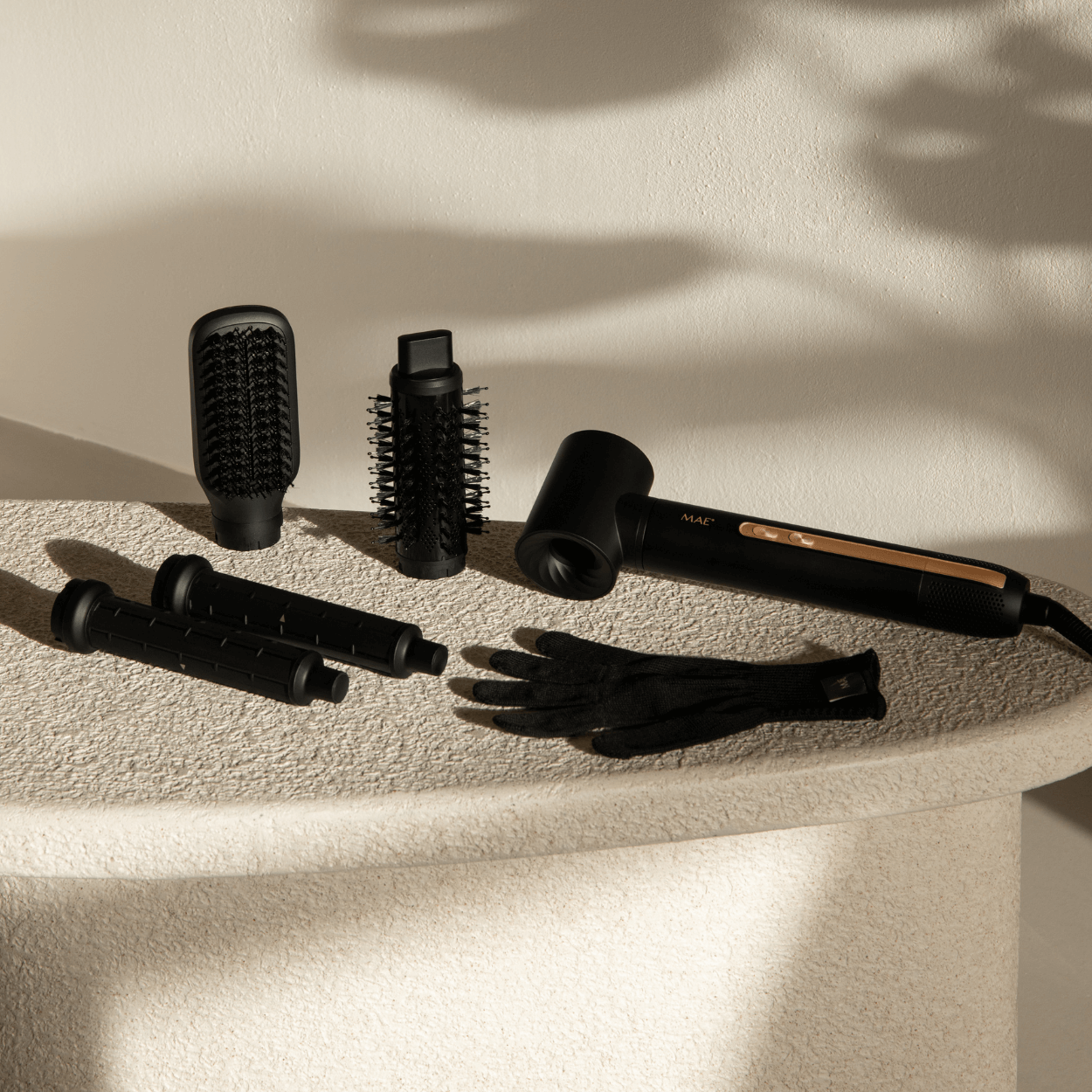 Een zwarte haardroger set met opzetstukken en handschoenen op steen.