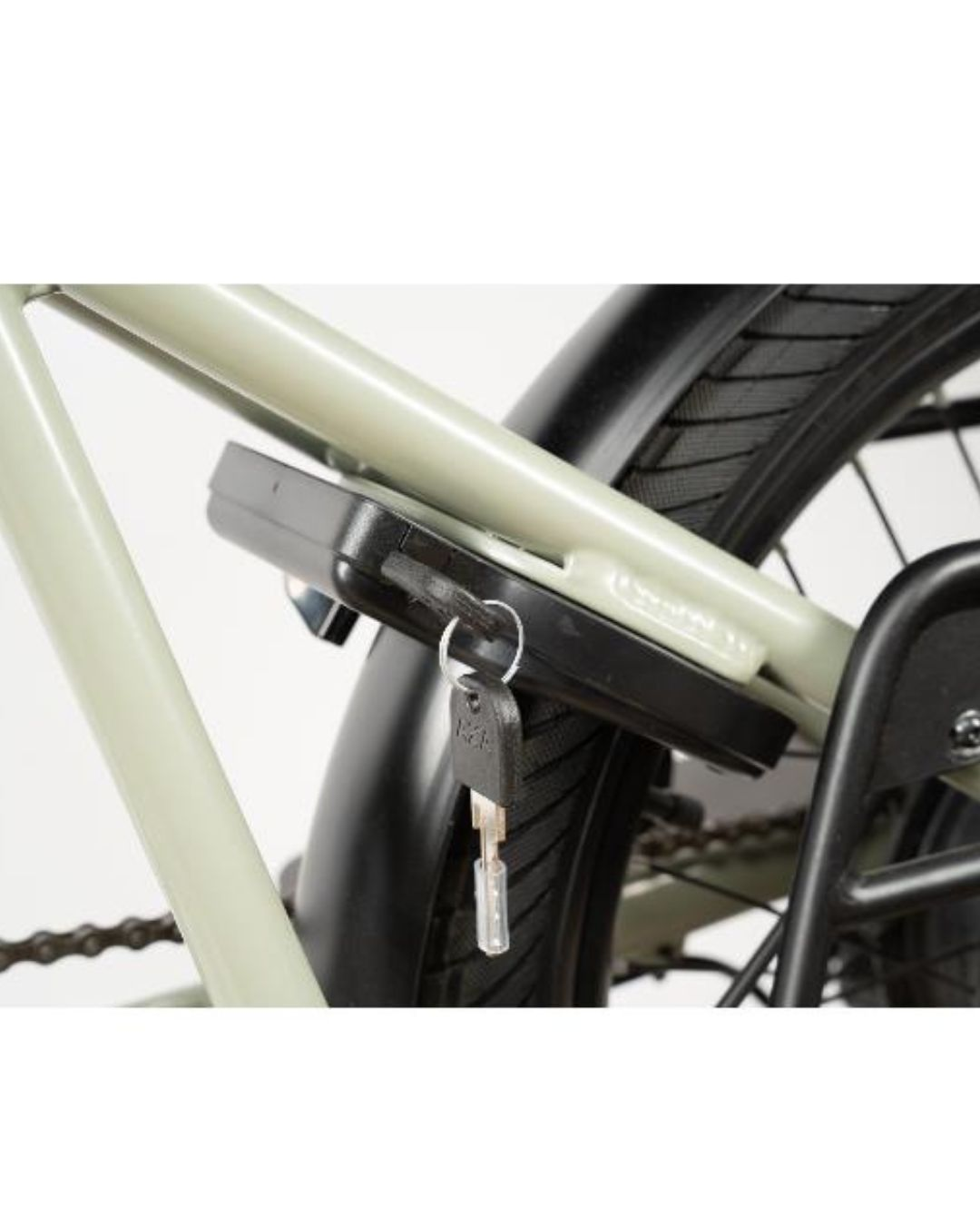 Una chiave pende da un lucchetto per bicicletta nero attaccato al telaio di una bicicletta verde chiaro.