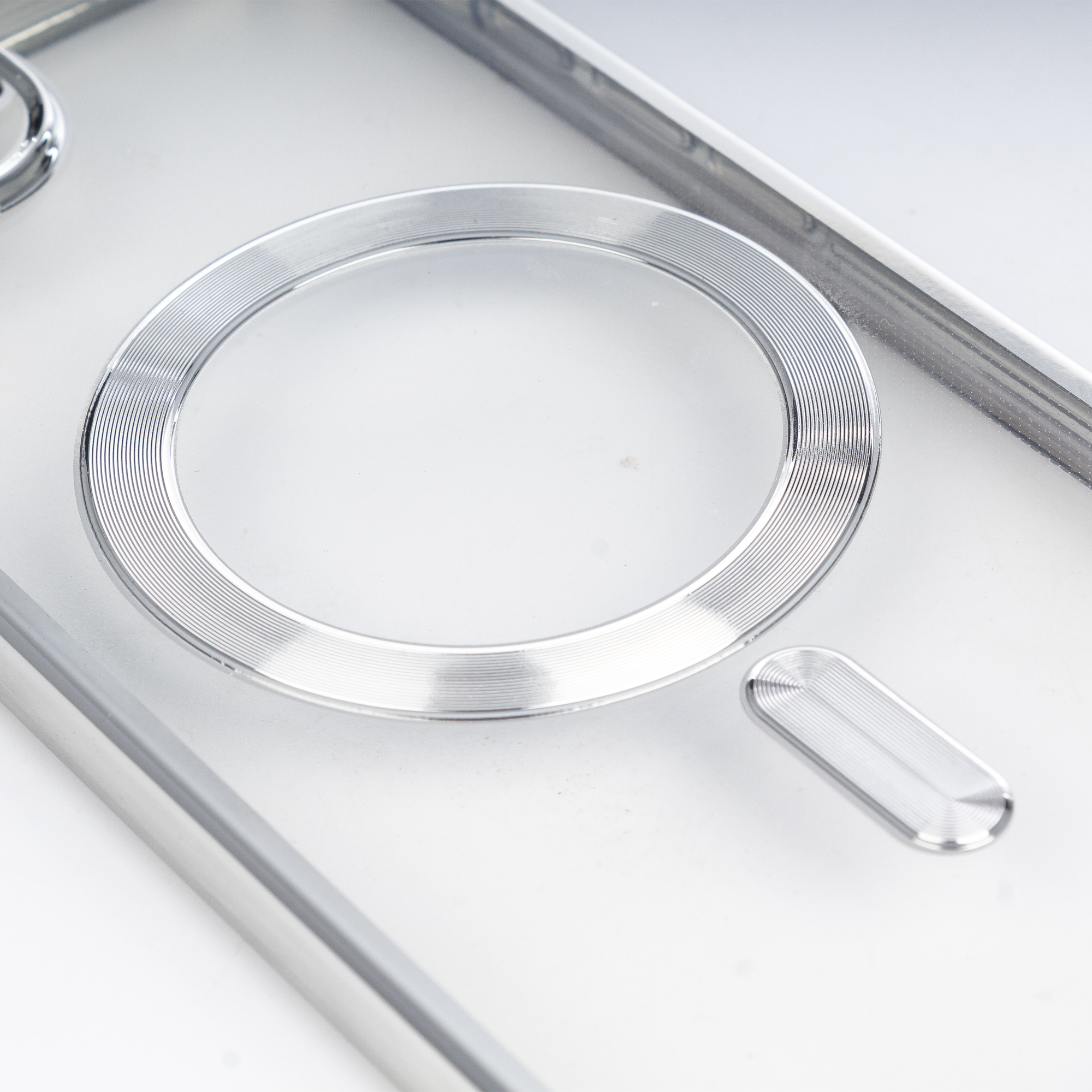 Un anello argentato scanalato e un elemento ovale più piccolo su sfondo bianco.