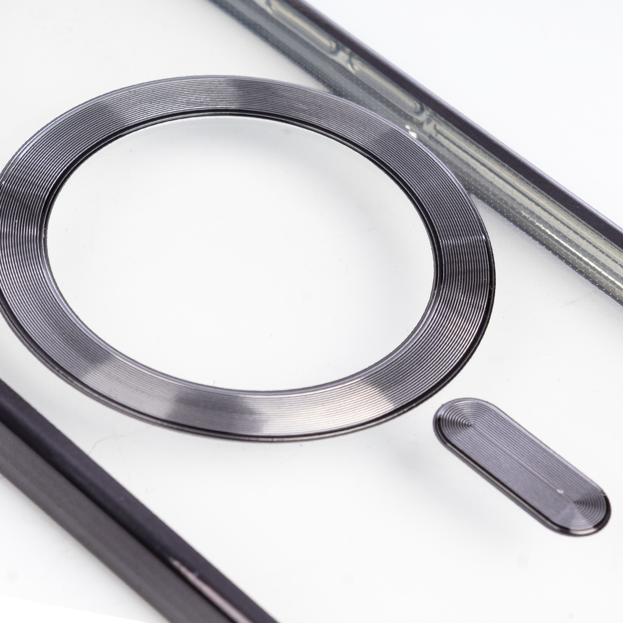 Un anello metallico scanalato e due aste su sfondo bianco.