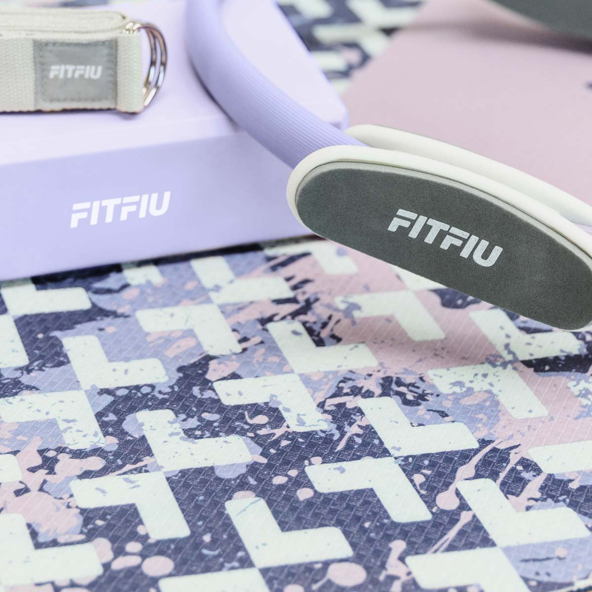 Un aro de Pilates lila con correa y caja beige, todo con logo FITFIU.