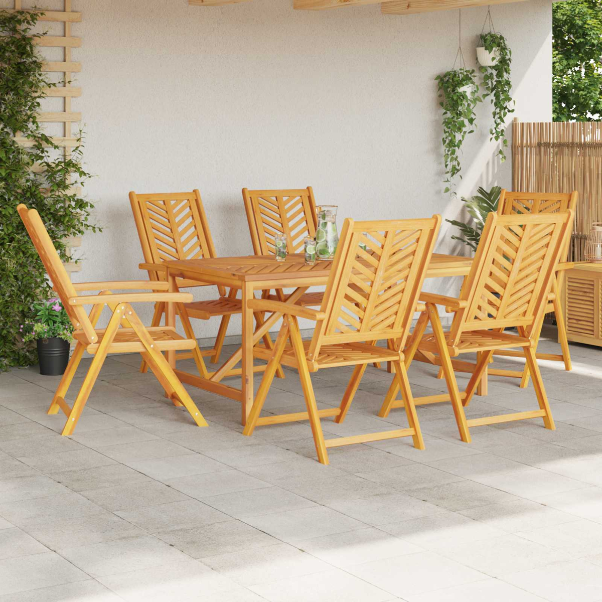 Ein Holztisch mit sechs Stühlen steht auf einer Terrasse, umgeben von Pflanzen.