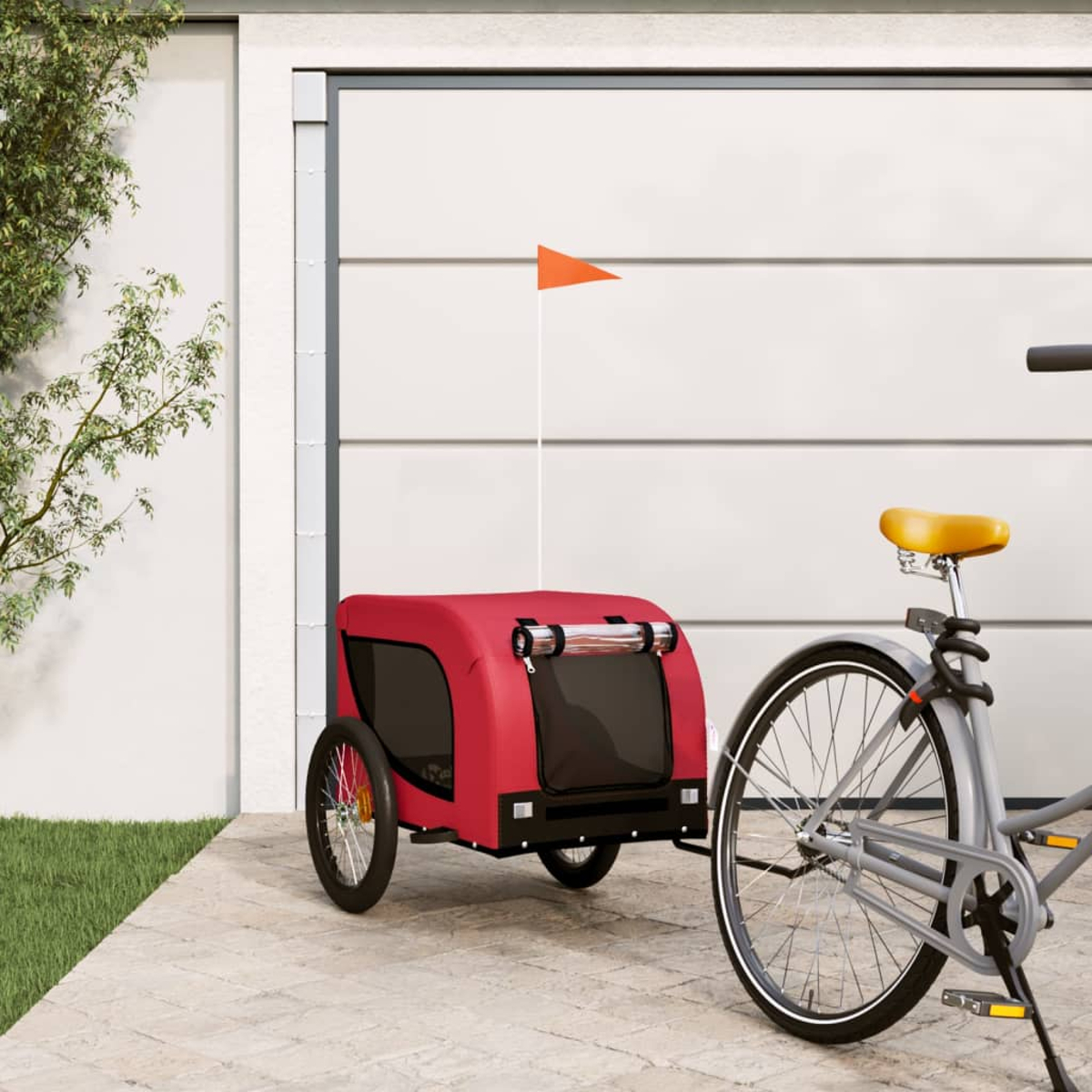 Ein roter Fahrradanhänger mit oranger Flagge, angekoppelt an ein Fahrrad.