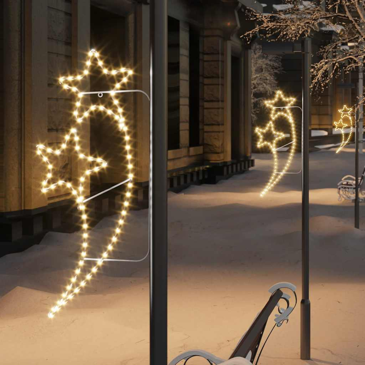 Drei Sterne-Lichterketten an Laternenpfählen im Schnee, Nacht.