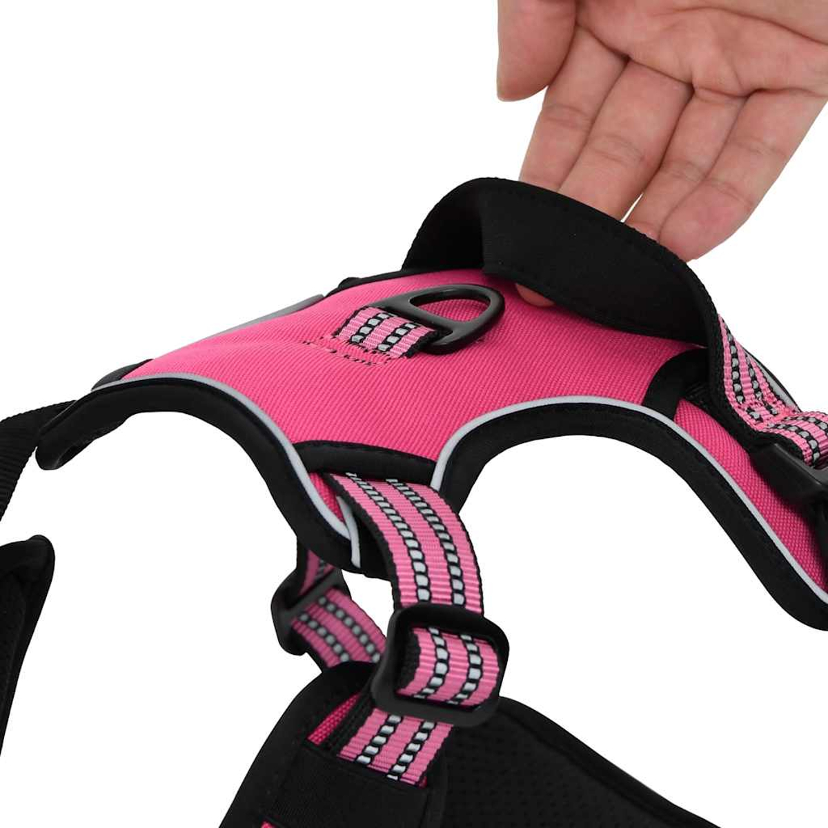 Eine Hand greift nach einer pinken Hundegeschirr mit schwarzen Akzenten und Reflektoren.