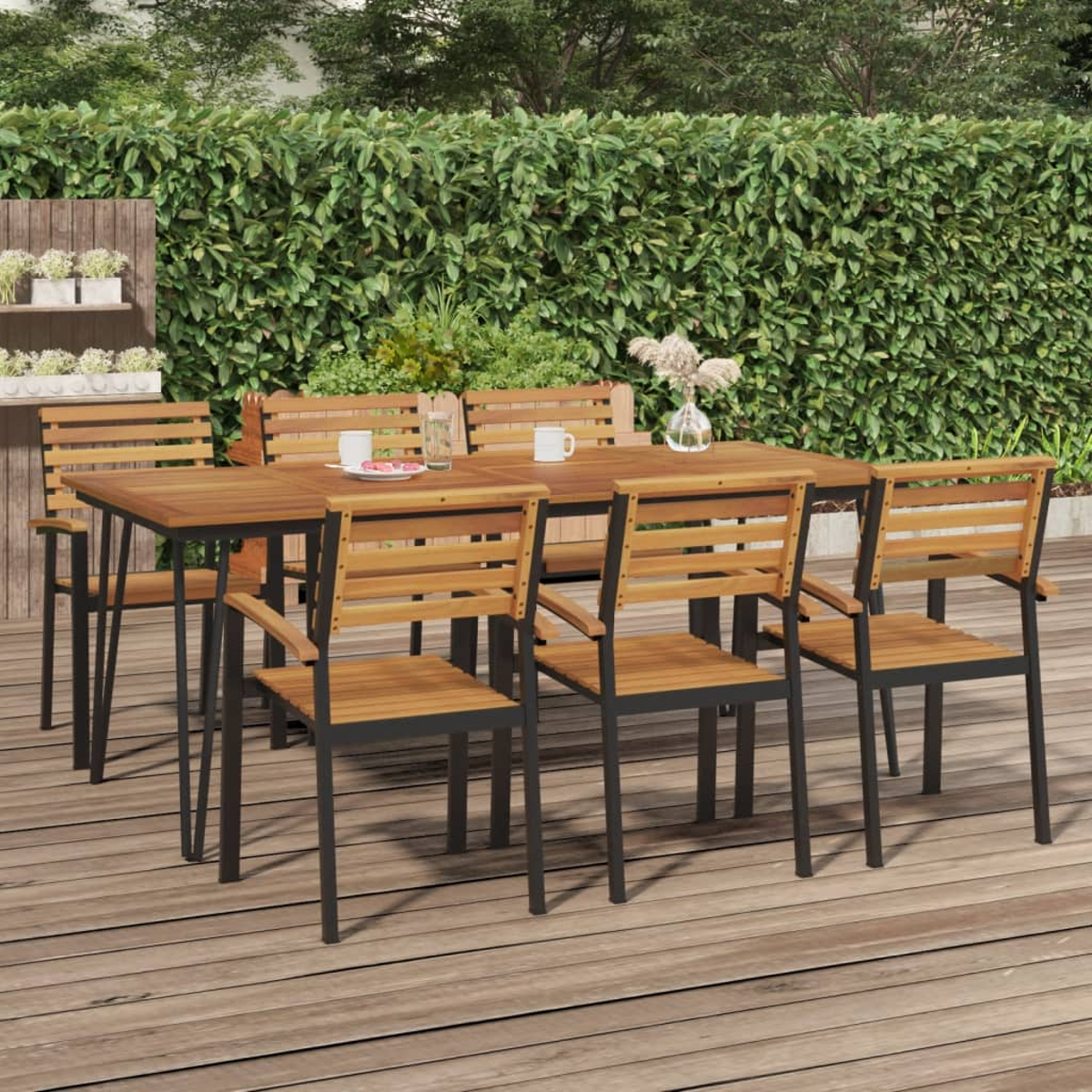 Ein Holztisch mit Stühlen und Bänken auf einer Holzterrasse, hinter einer Hecke.