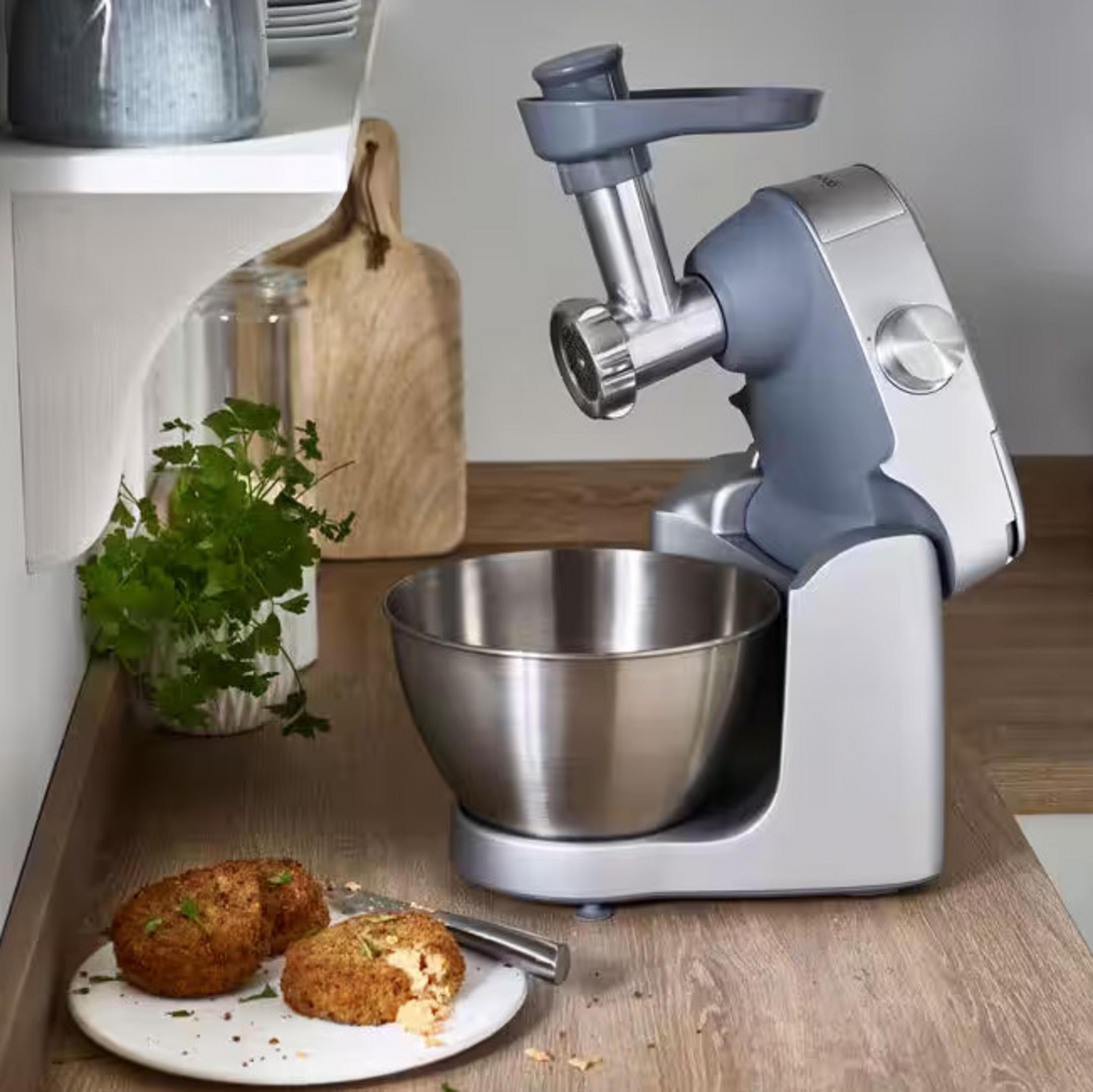 Robot kuchenny z przystawką maszynki do mięsa, misą ze stali nierdzewnej i dwoma kotletami.