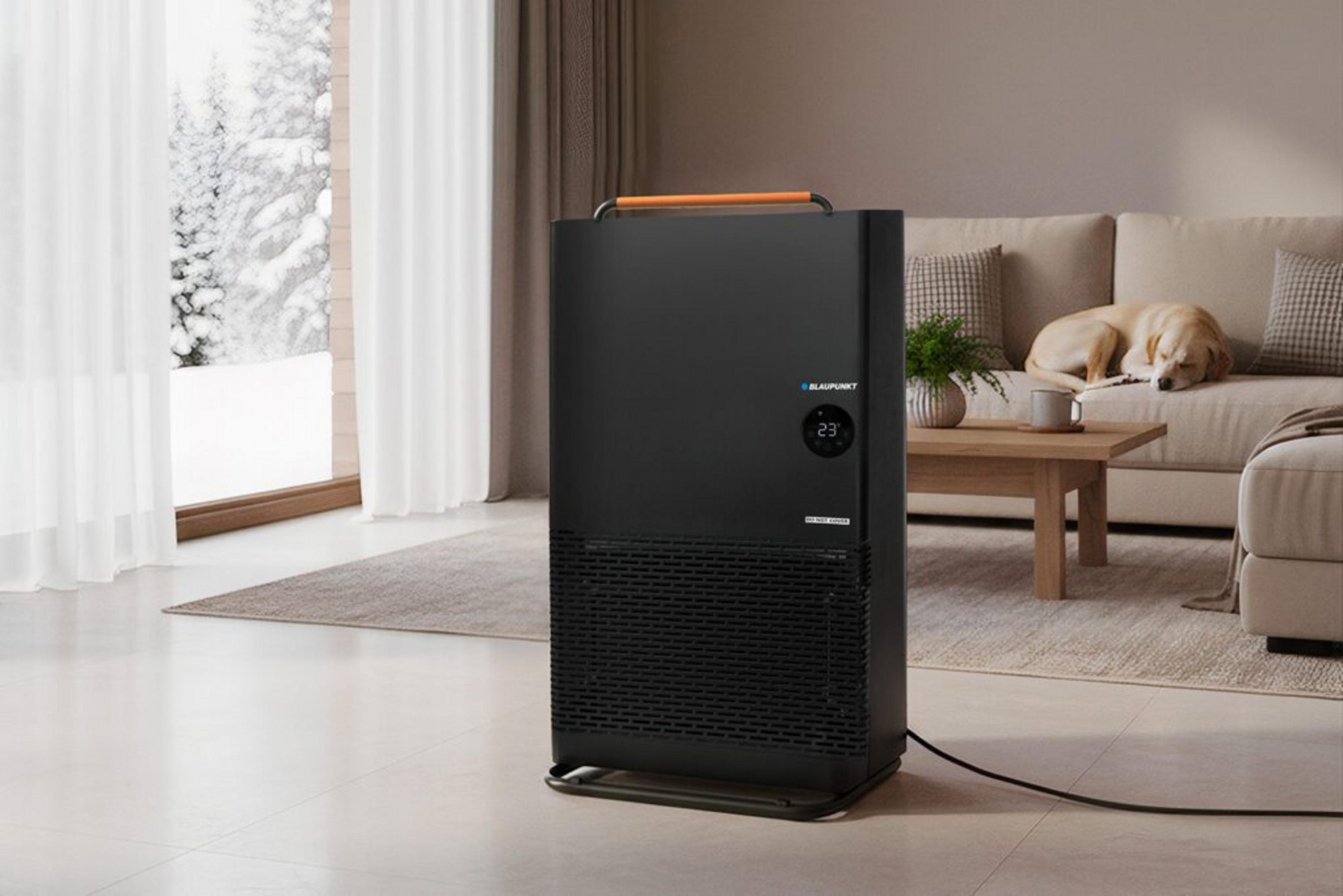 Un purificatore d'aria nero in un soggiorno vicino a una finestra innevata.