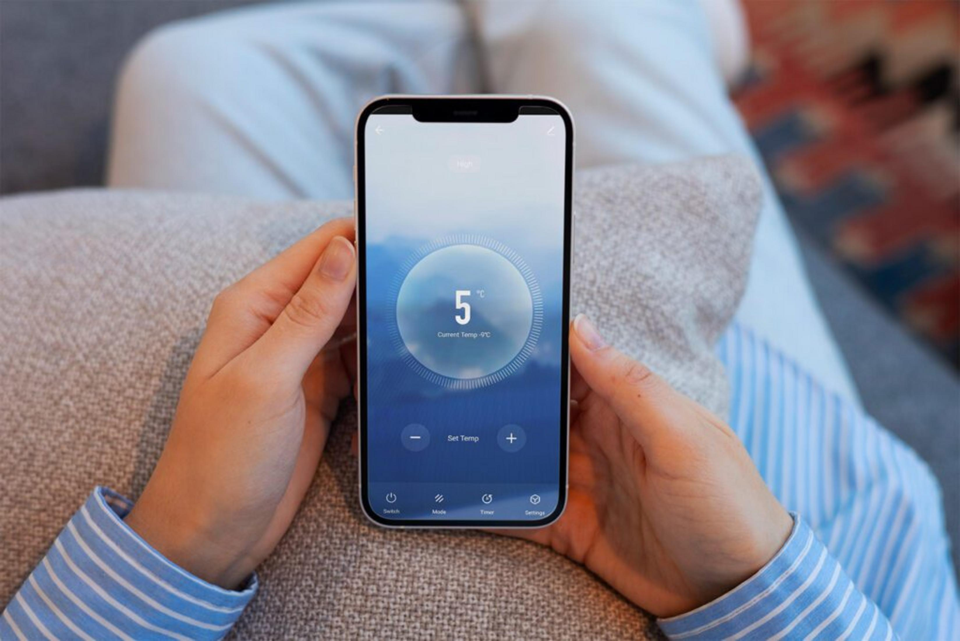 Una persona tiene uno smartphone con un'app termostato. Temp attuale 5°C.