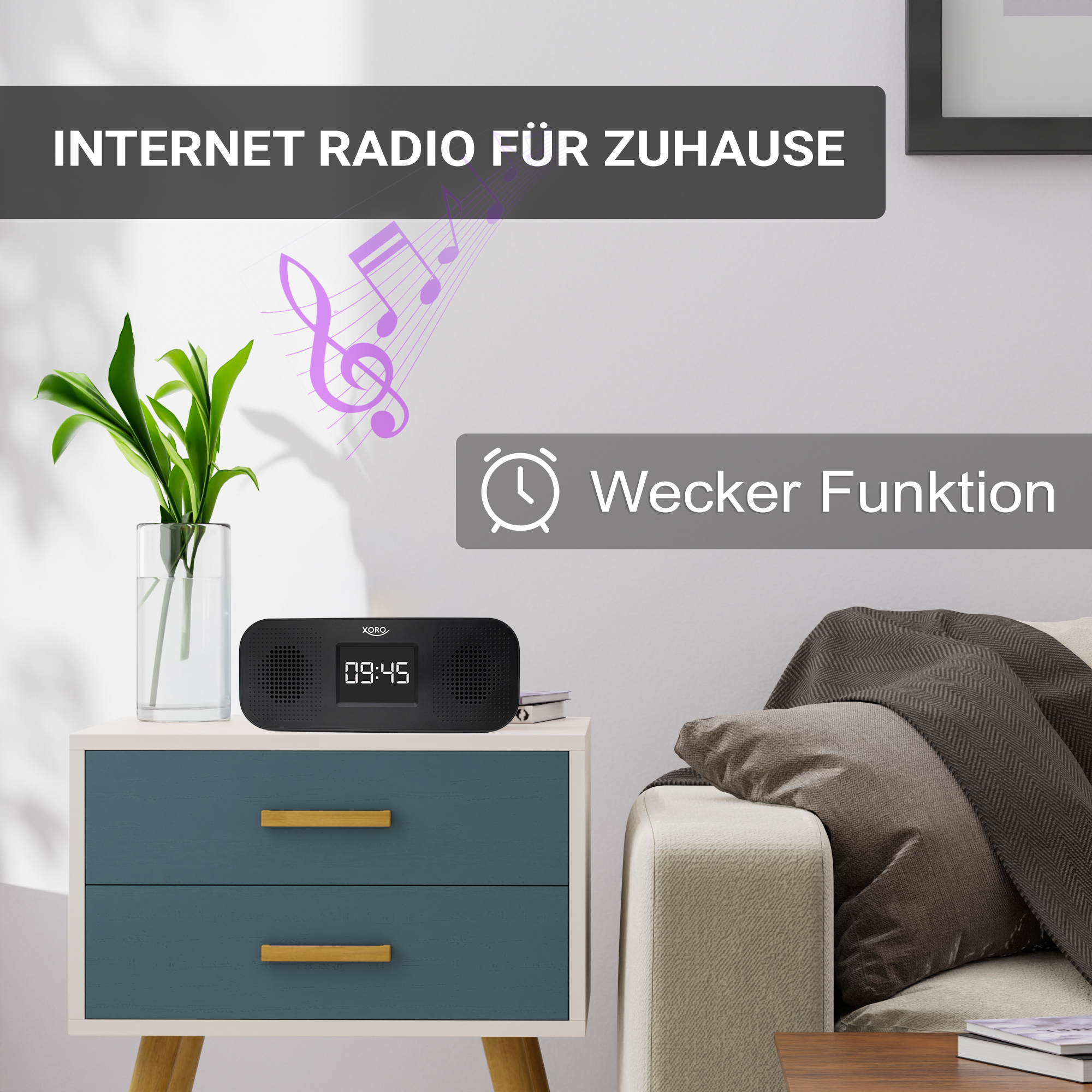 Ein schwarzer Internetradio-Wecker mit digitaler Anzeige auf einem Nachttisch neben einer Pflanze.