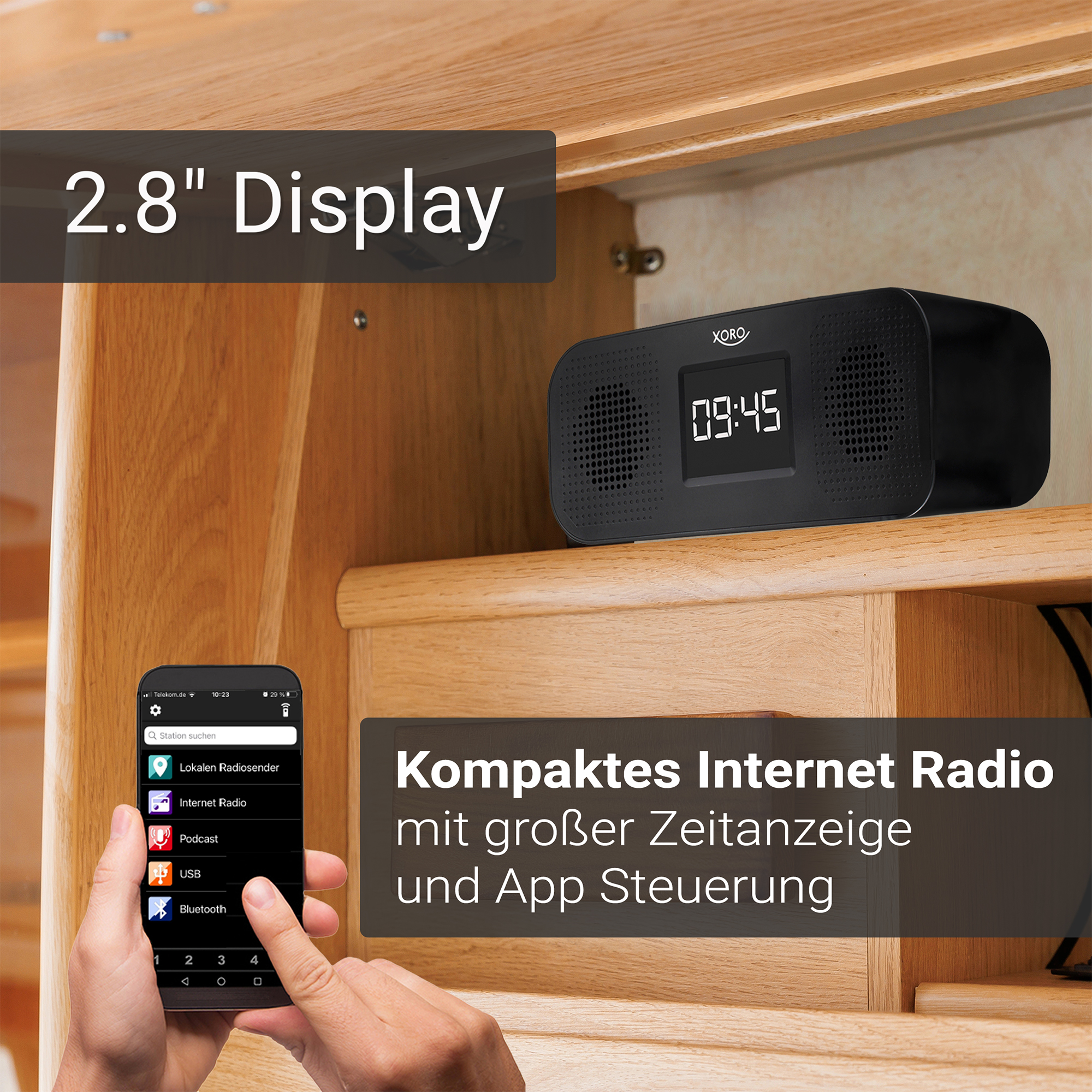 Ein schwarzes Internetradio mit 2.8" Display steht auf einem Holzregal. Eine Hand hält ein Smartphone mit Radio-App.