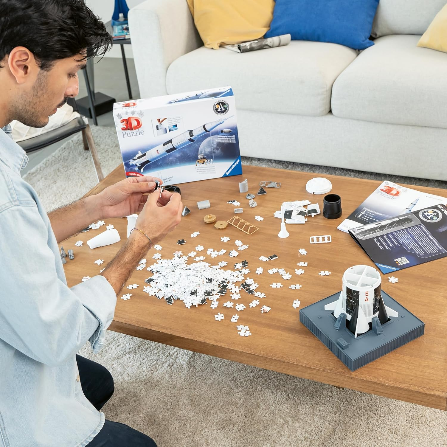 Mężczyzna składa trójwymiarową rakietę na drewnianym stole.