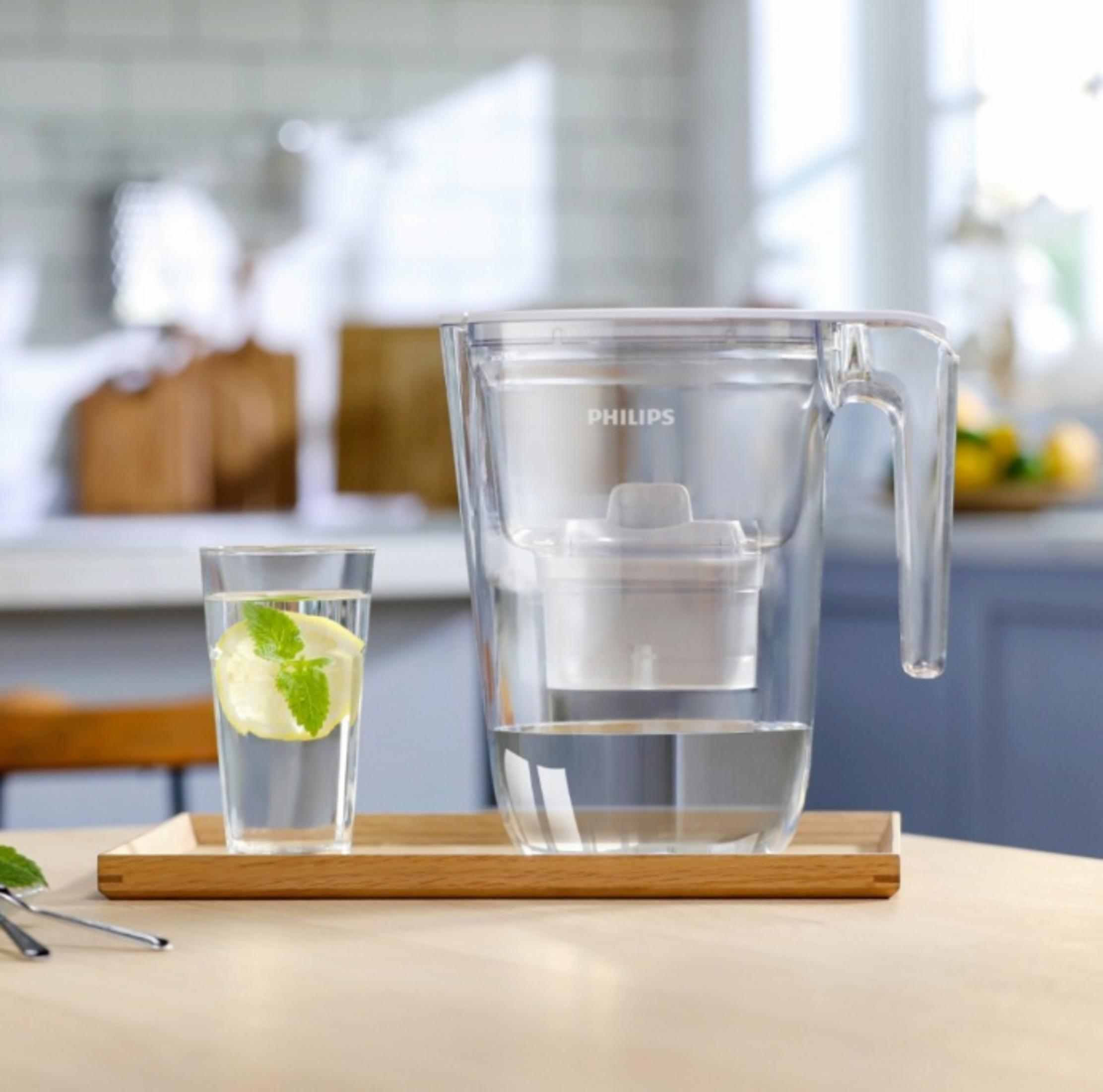 Un bicchiere d'acqua con limone e menta accanto a una caraffa filtrante Philips.