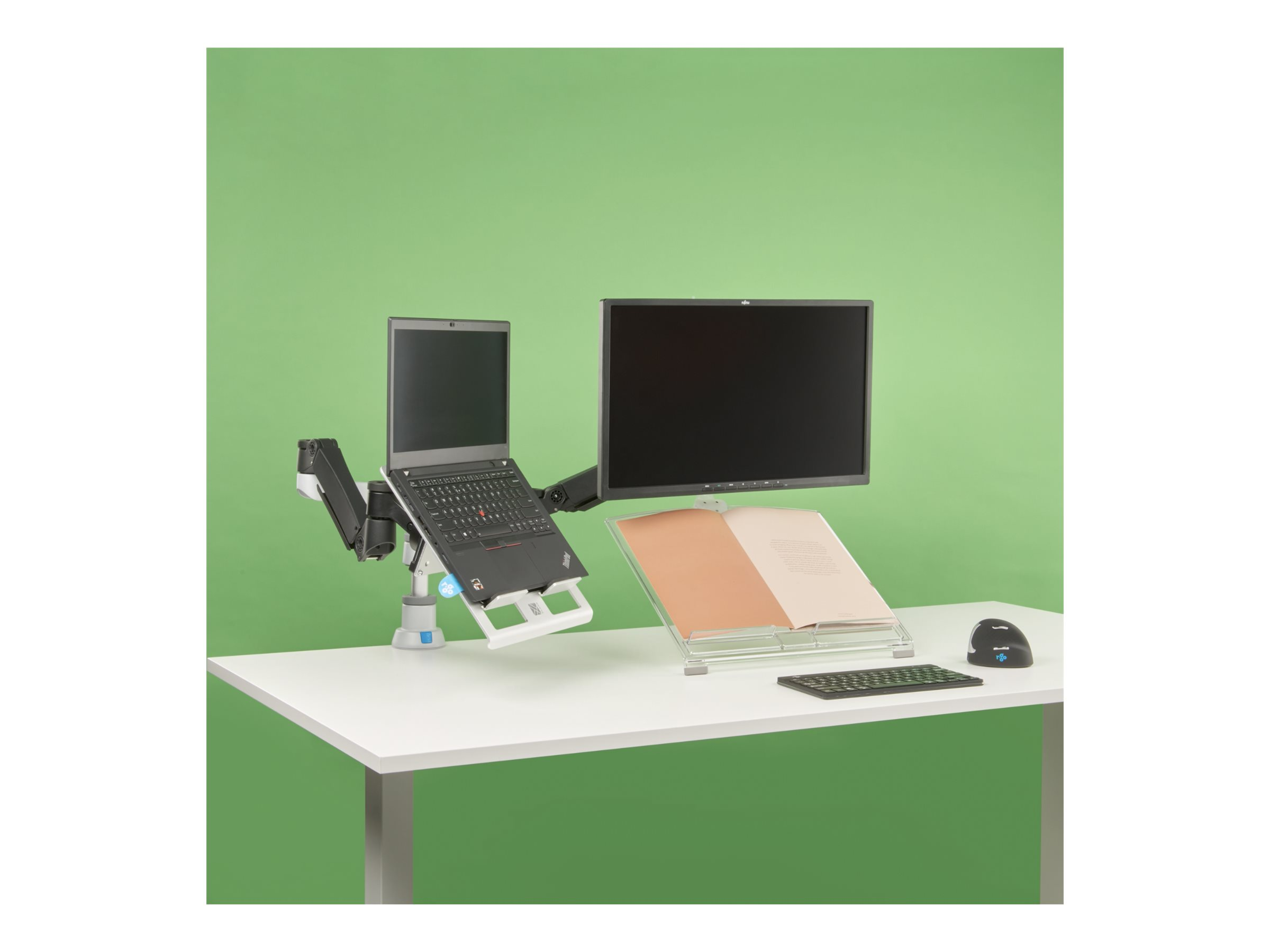 Een laptop en monitor staan op een bureau voor een groene achtergrond.