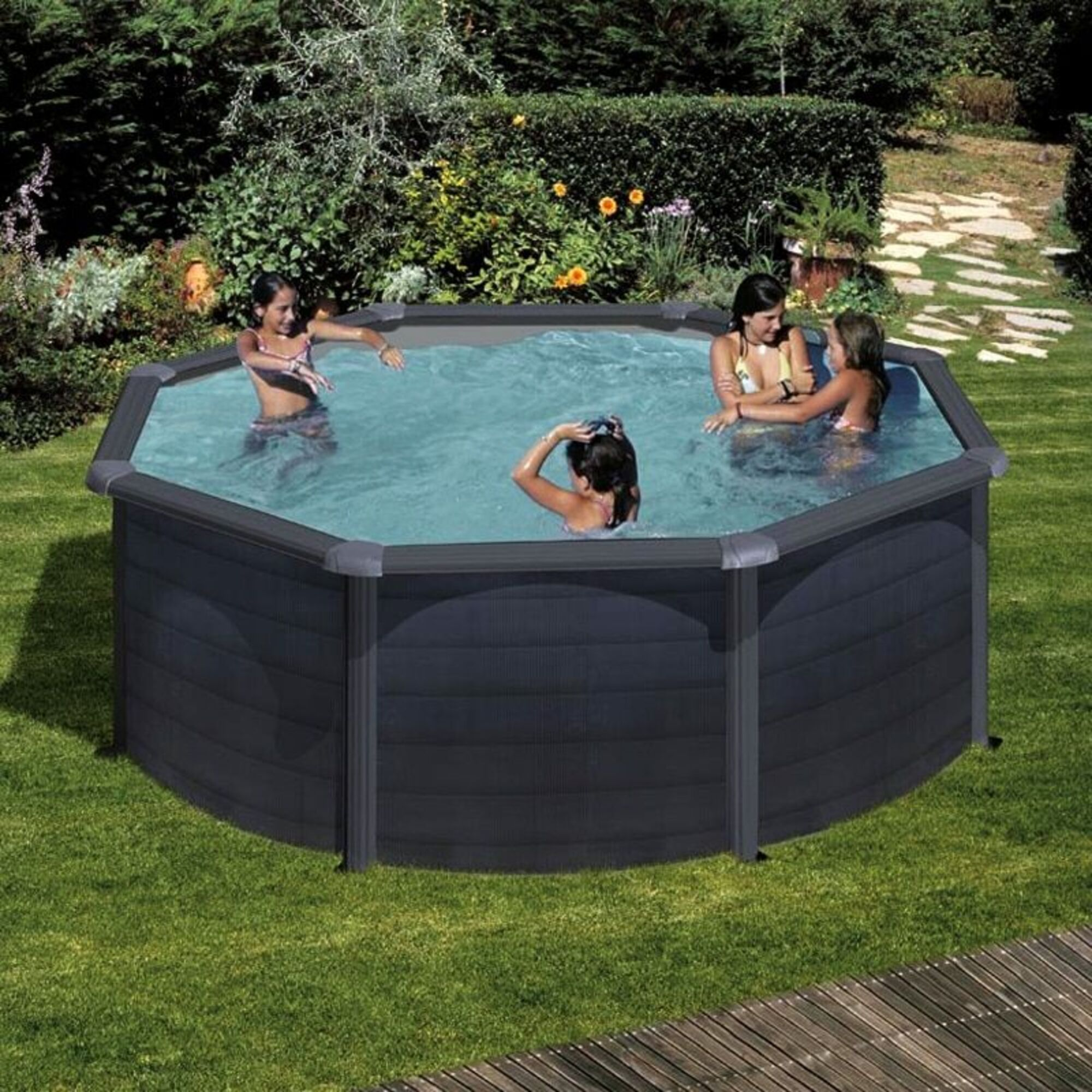Cuatro chicas chapotean en una piscina octogonal en un jardín.