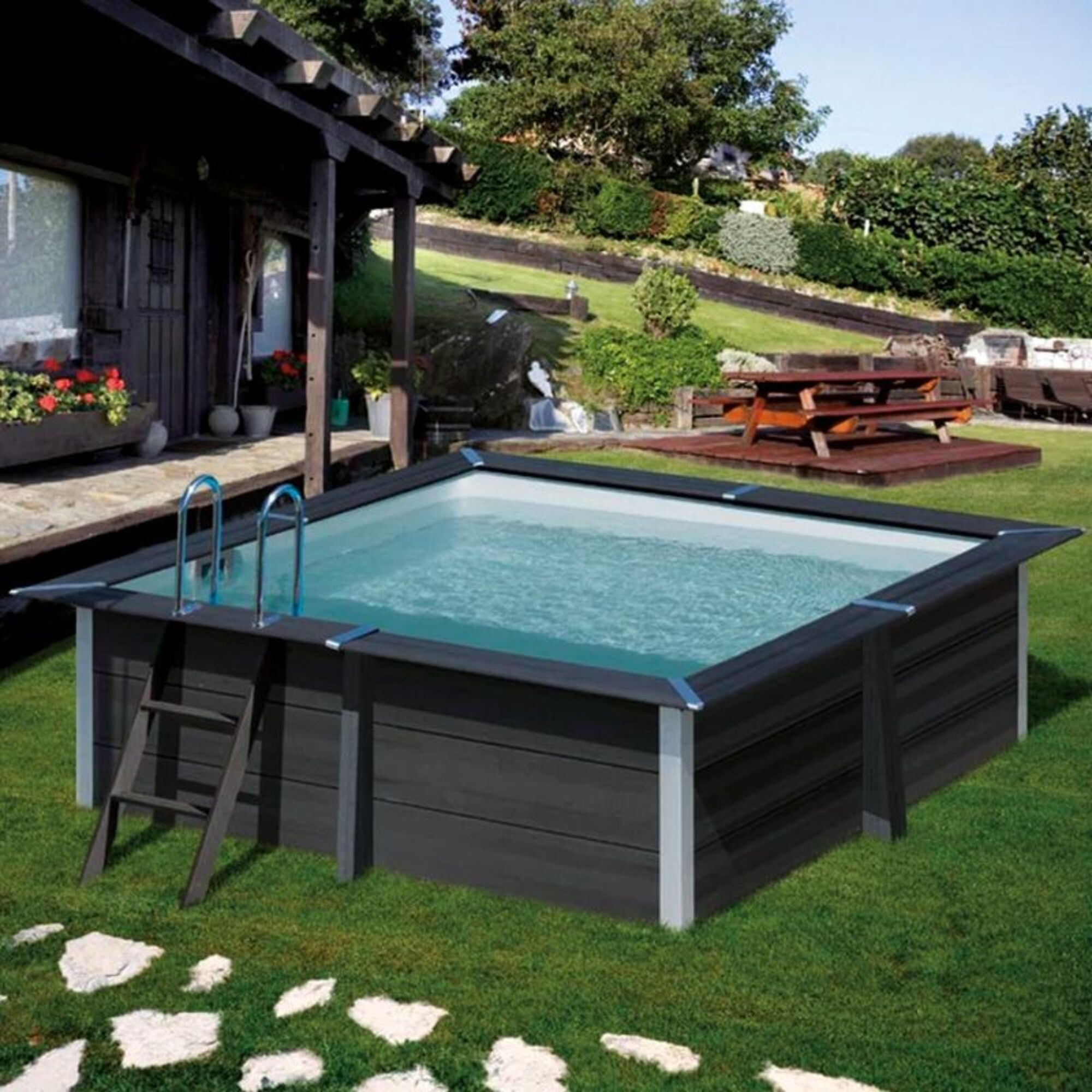 Una piscina rectangular con revestimiento oscuro y escalera plateada en un jardín.