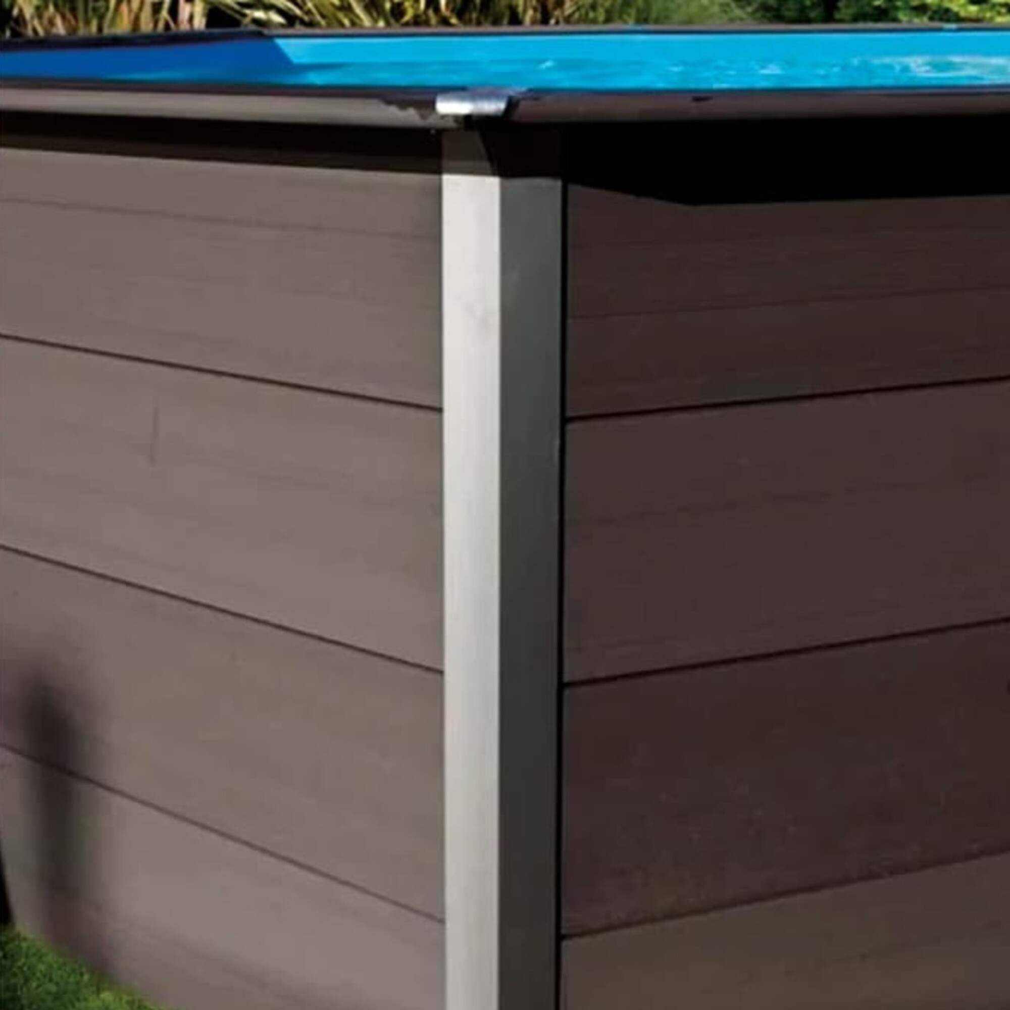 Una piscina rectangular con revestimiento de madera marrón y cubierta azul.