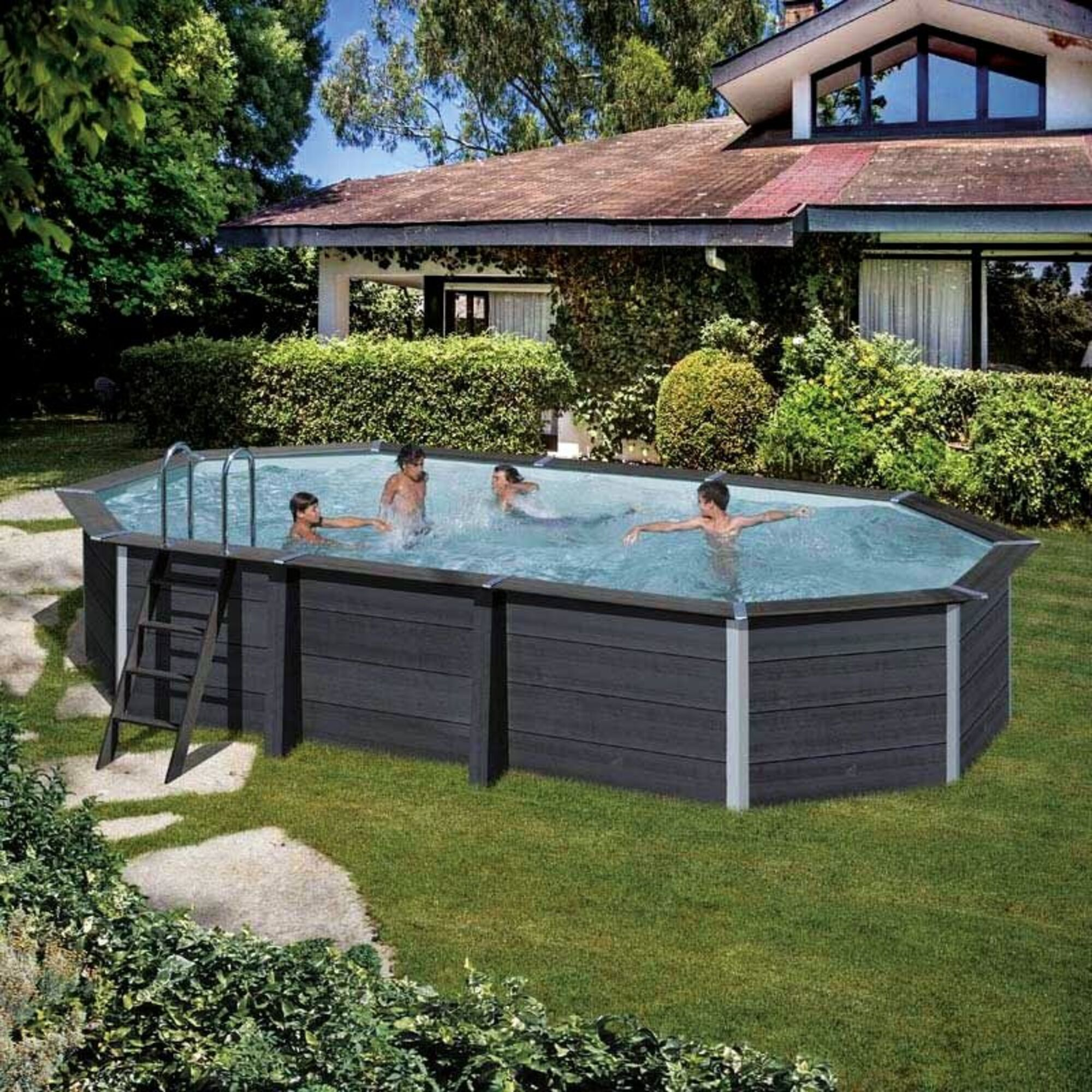Cuatro personas nadan en una piscina exterior octogonal frente a una casa.