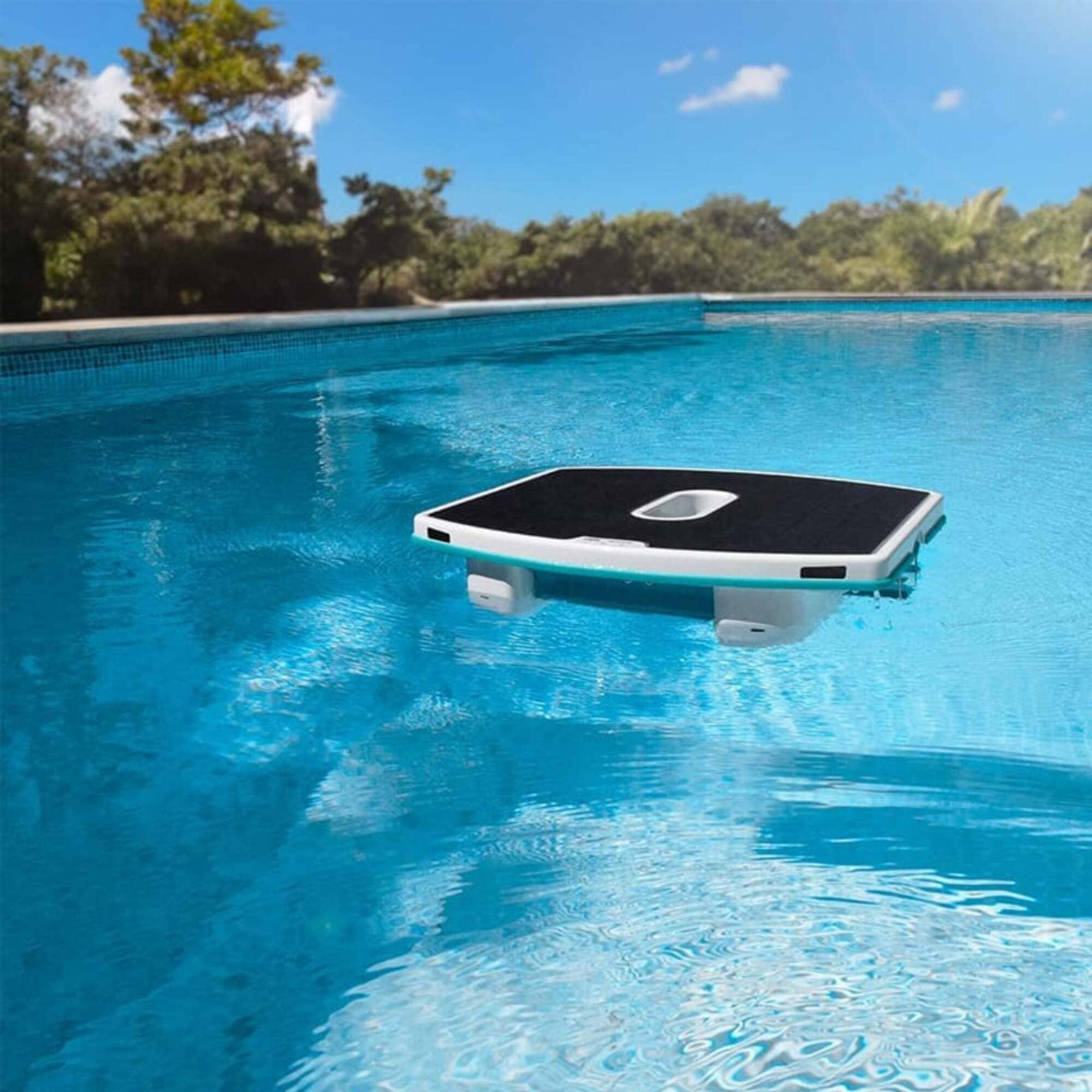 Un pulitore per piscina nero galleggia sull'acqua turchese di una piscina.