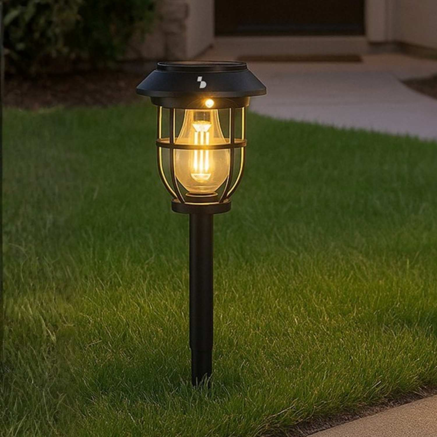 Una lampada da giardino solare nera con design a gabbia sull'erba.