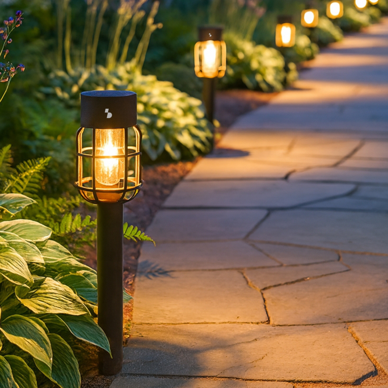 Sentiero in pietra in giardino, illuminato da lanterne, circondato da piante verdi.