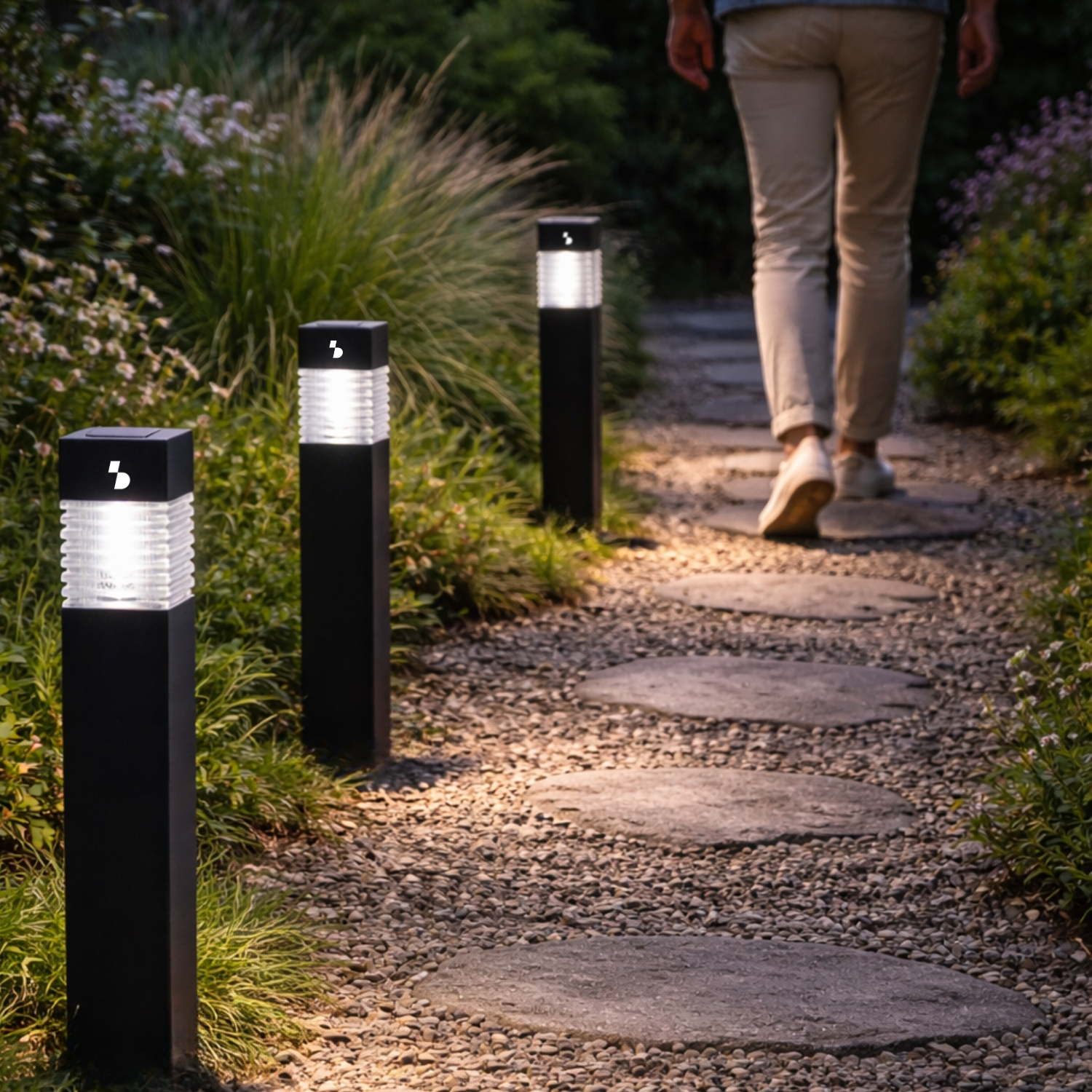 Un sentiero con pietre di passaggio tra ghiaia e illuminazione, una persona si allontana.