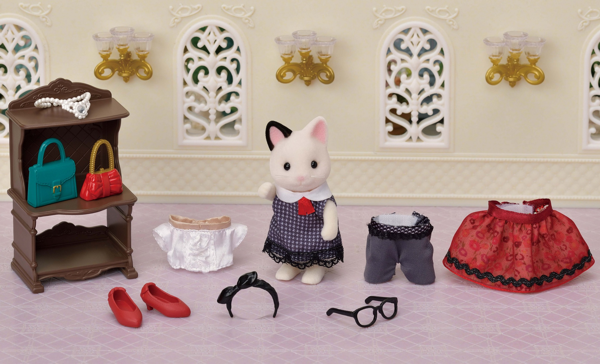 Eine Spielzeugkatze mit Kleidung und Accessoires wie Taschen, Schuhen und Schmuck.