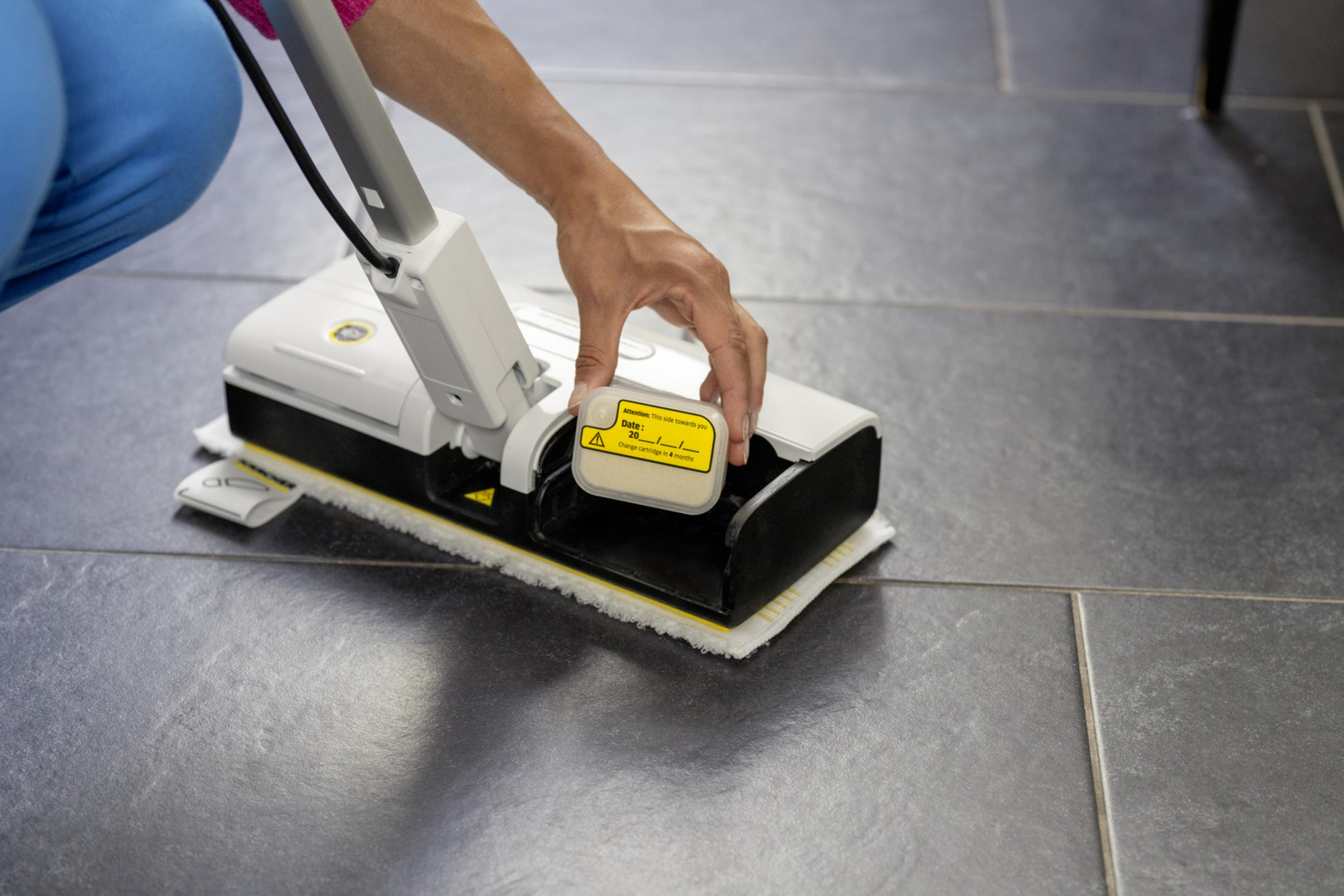 Una mano inserisce una cartuccia gialla in un pulitore per pavimenti.