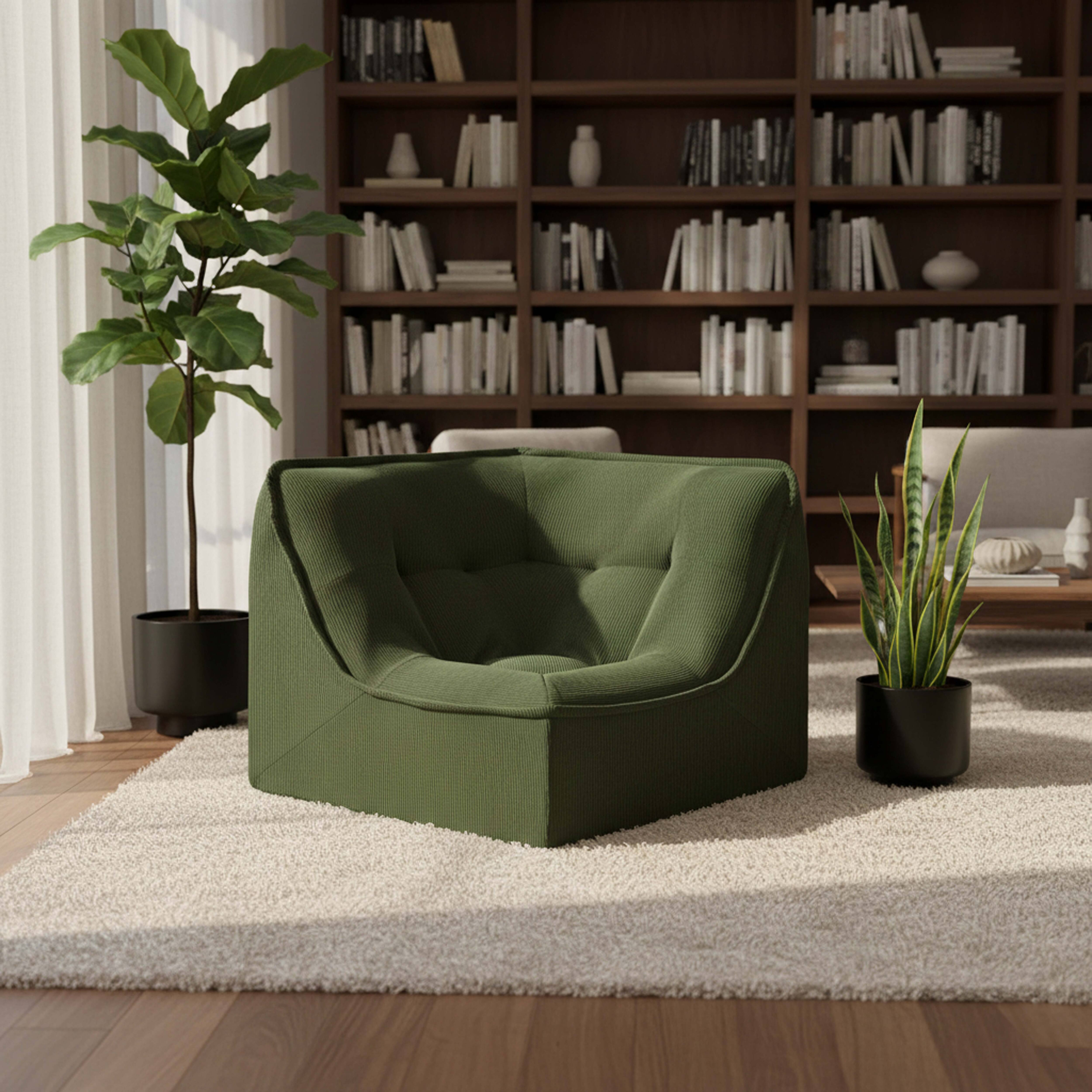 Ein grüner Cord-Sessel steht auf einem Teppich vor einem Bücherregal.