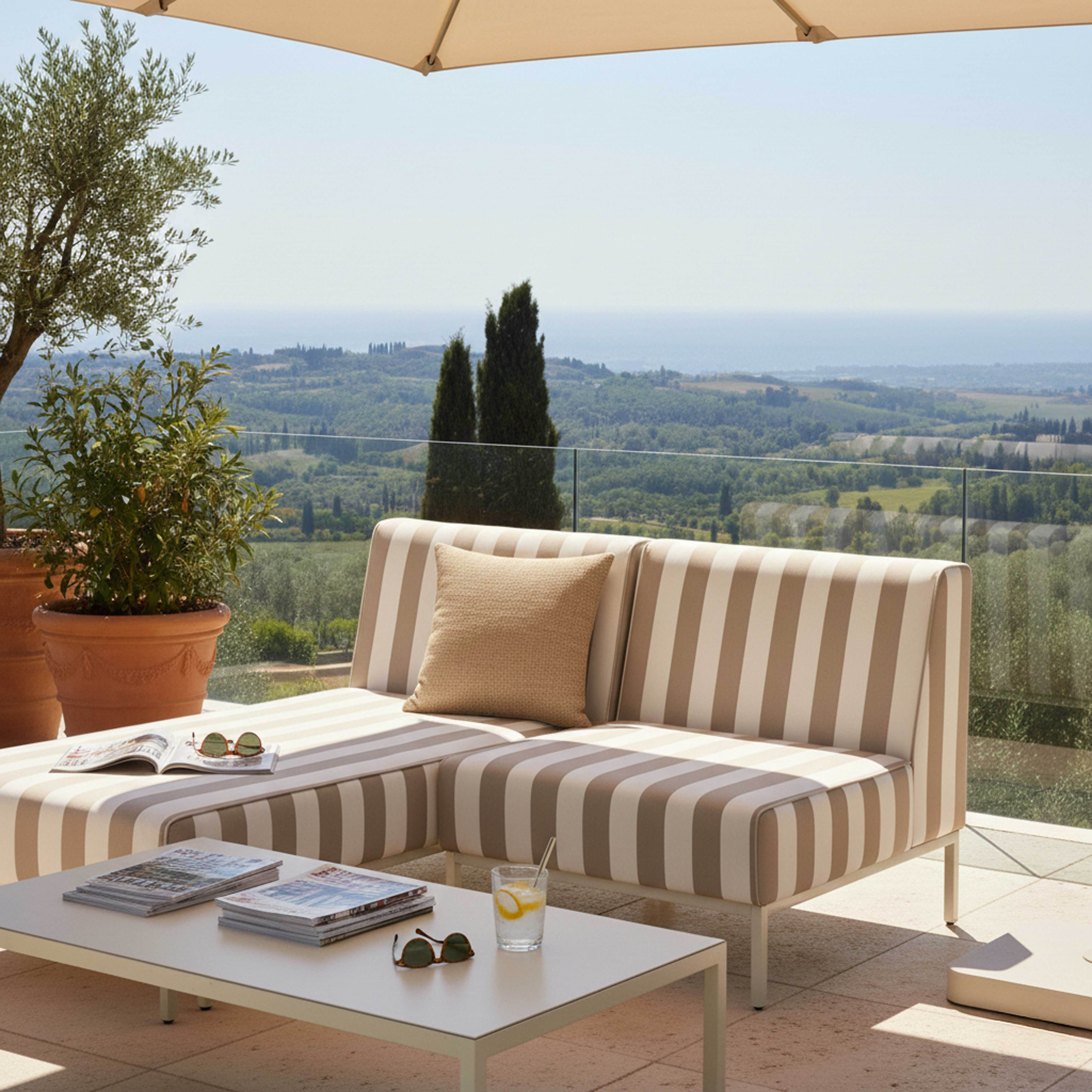 Gestreiftes Sofa mit Kissen auf einer Terrasse mit Blick auf eine hügelige Landschaft.